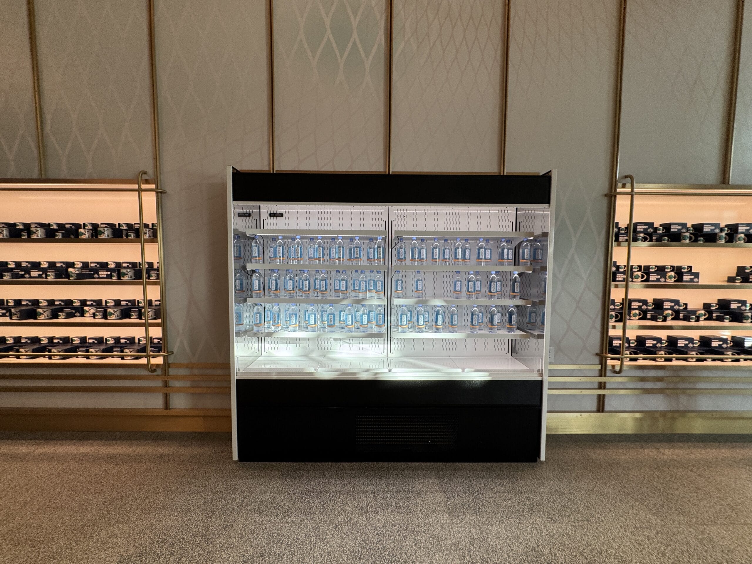 Glass fridge at a Disney Park Starbucks, stocked with clear water bottles and flanked by Disney-themed shelves and containers.