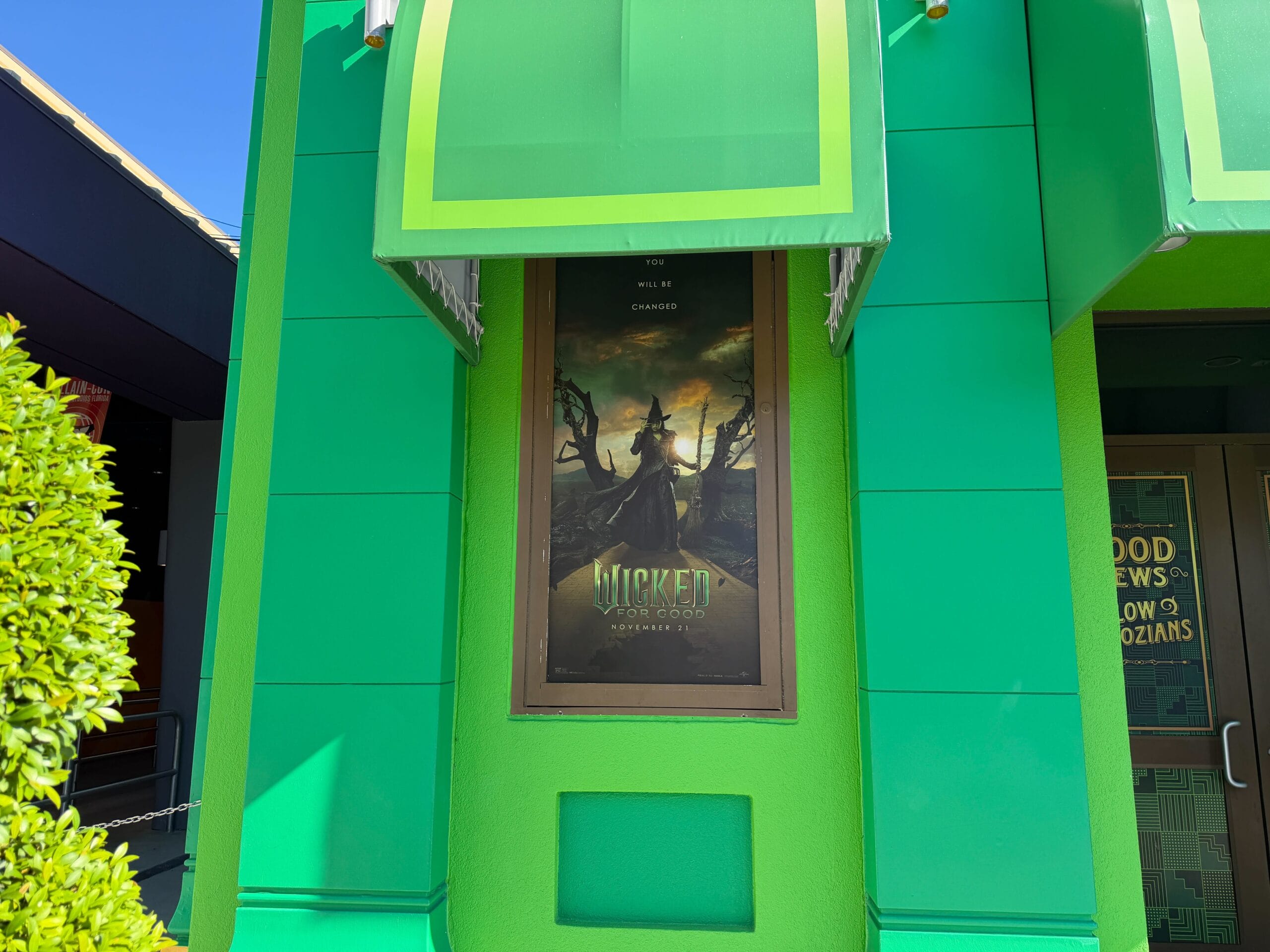 Wicked poster on a vibrant green wall at Universal Studios Florida, showing a witch—quite a contrast to Disney castle magic nearby.