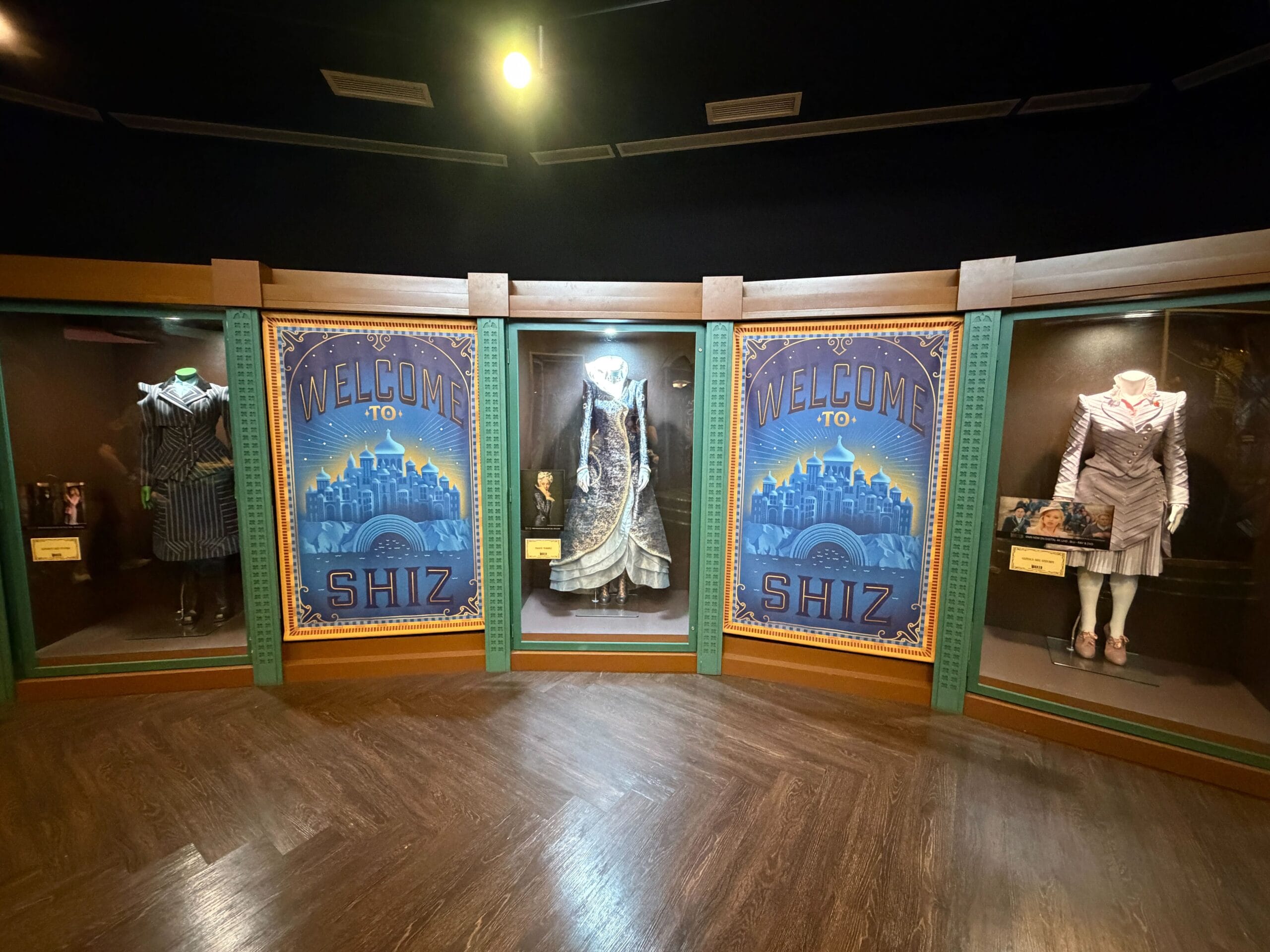 Four Wicked costumes in glass cases stand between two Wicked posters at Universal Studios Florida—not a Disney castle in sight.