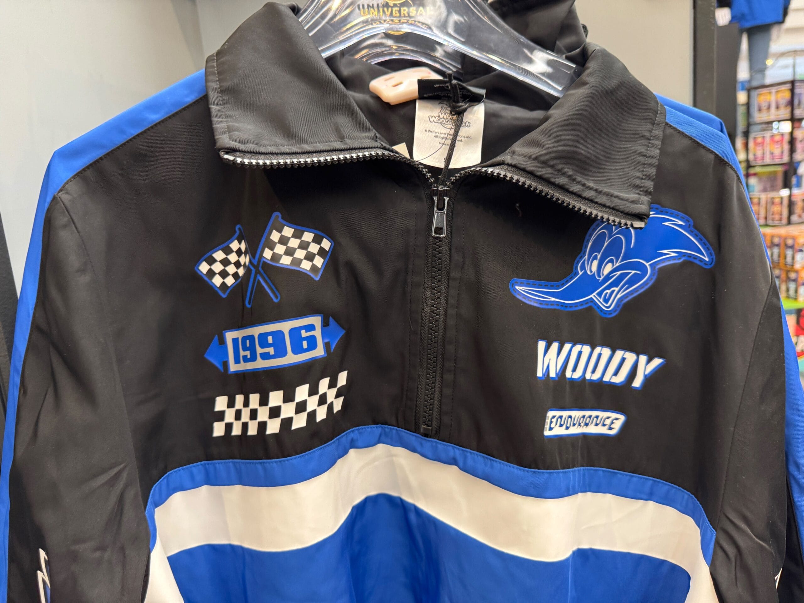 Black and blue jacket with racing checks, "1996", and a cartoon blue woodpecker head labeled "Woody.