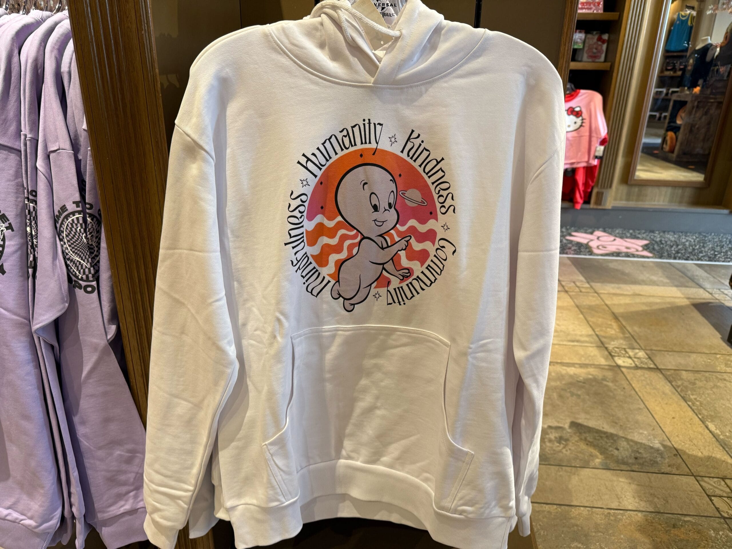 White hoodie with Casper and a circular text design—seen at Universal Studios Hollywood, not at Disney Parks like Disneyland’s castle.