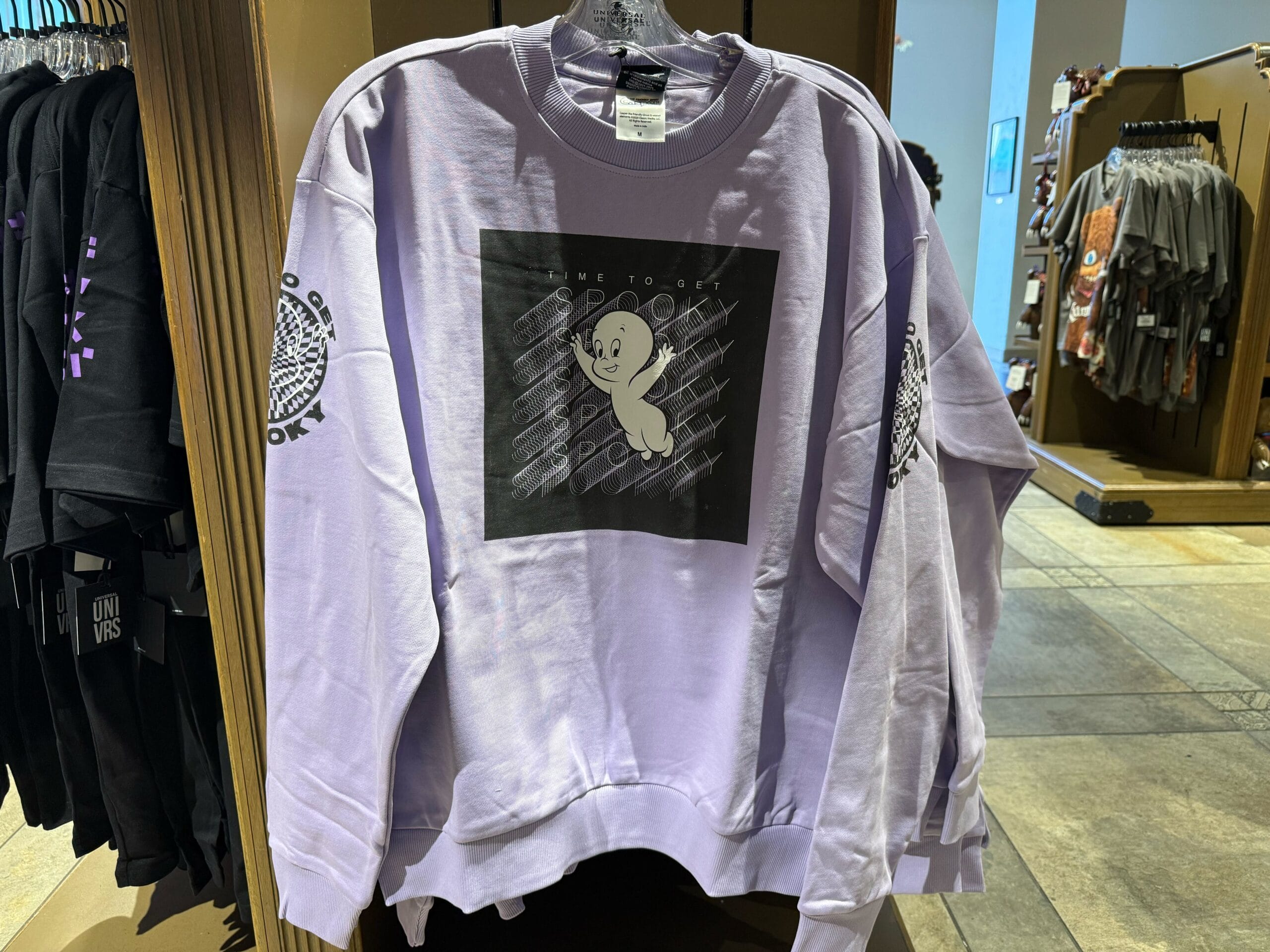 Lavender Casper Apparel sweatshirt with cartoon ghost and "Time to get spooky" at Universal Studios, not Disney castle backdrop.