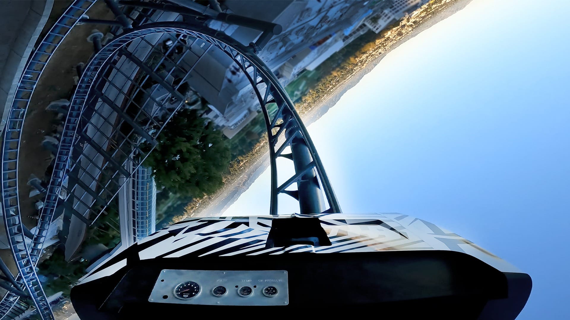 Front seat view on a Disney park roller coaster rushing down a steep track, blue sky and park scenery in the background.