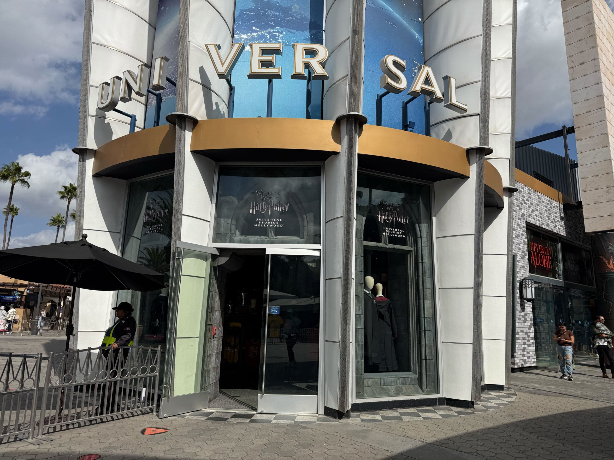 Universal Studios Hollywood store entrance with glass doors and "UNIVERSAL" sign, not resembling any Disney castle design, blue sky above.