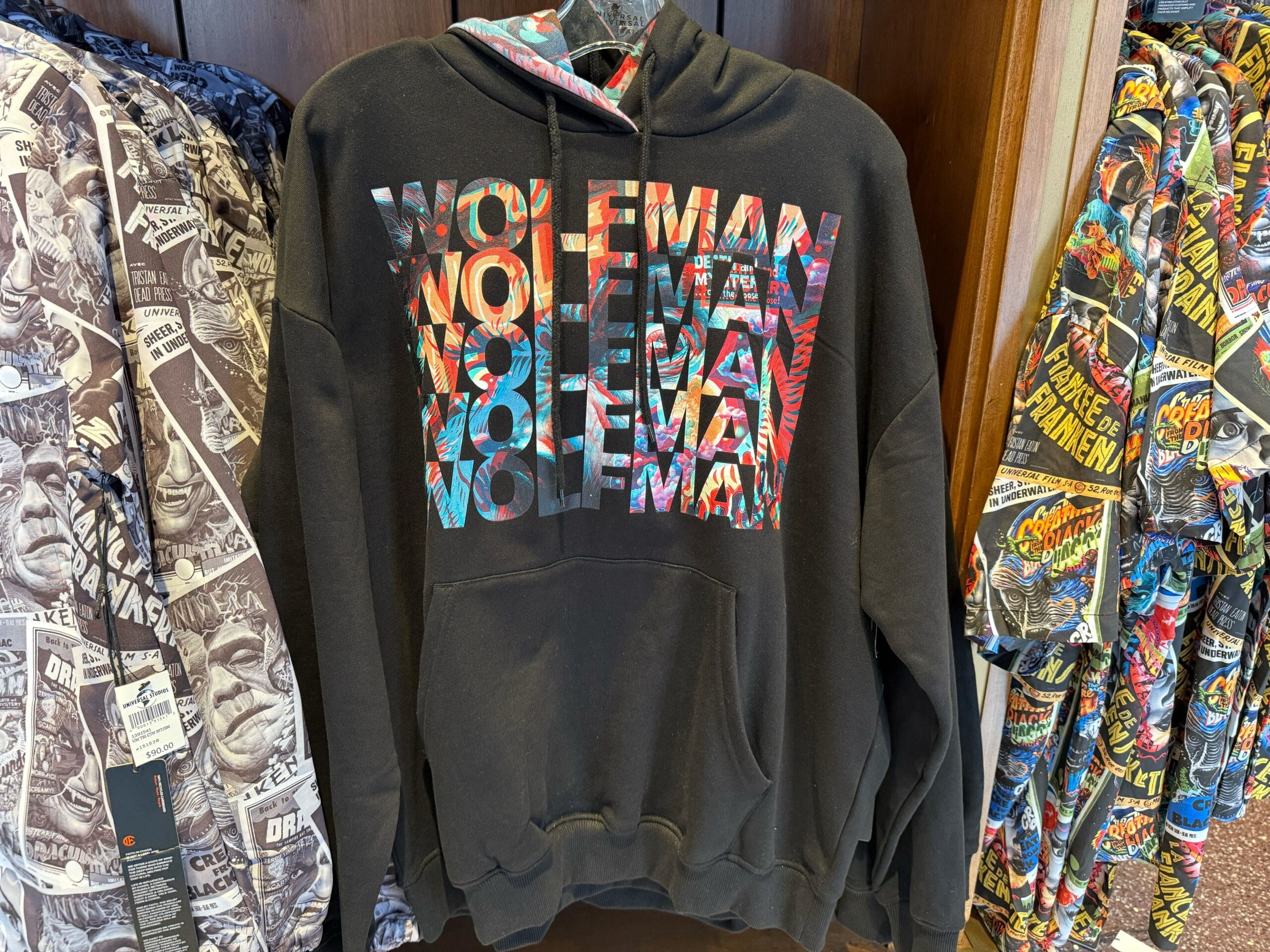 Black hoodie from the Universal Monsters Collection with colorful "WOLFMAN" text, surrounded by graphic jackets—not a Disney castle.
