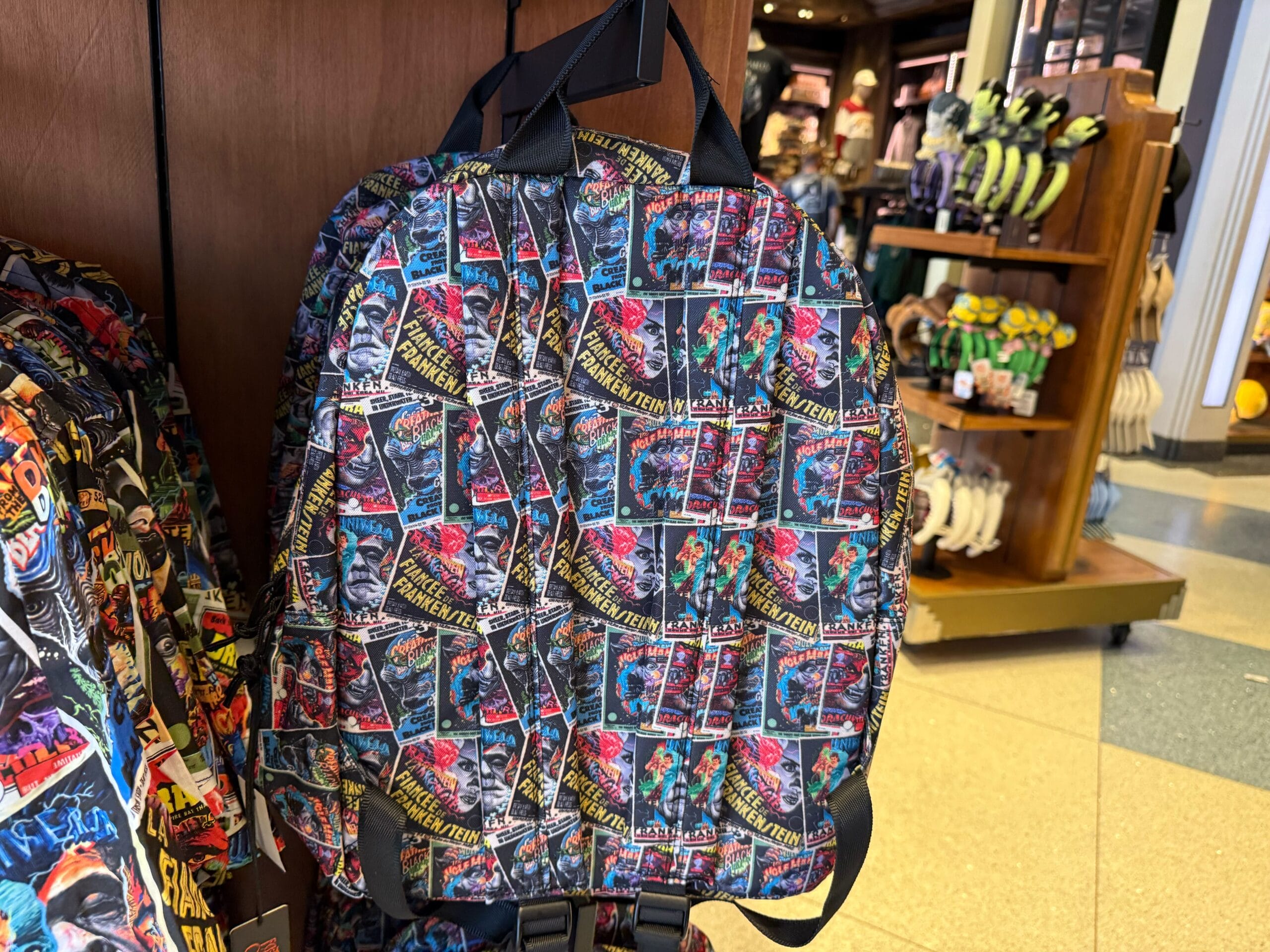 A vibrant backpack with retro Marvel comic covers, seen on a rack—distinctly at Universal Studios, not a Disney park castle locale.