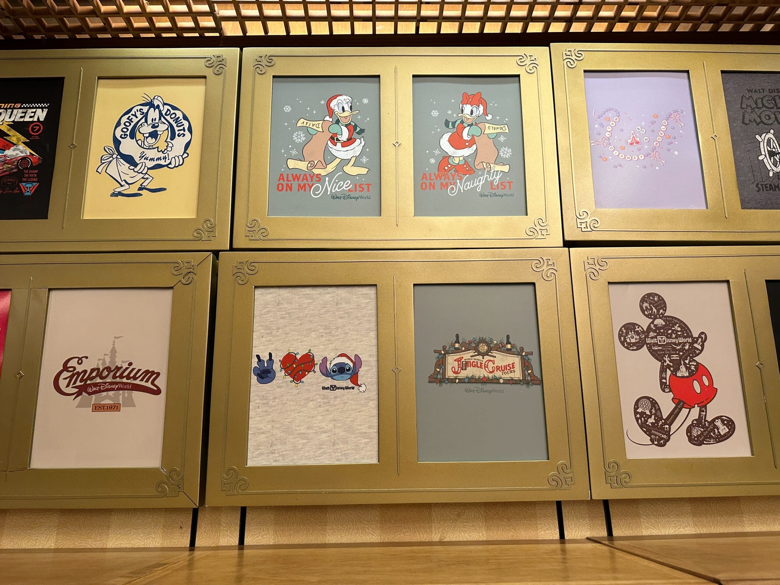 Display case featuring Disney Parks t-shirts, with designs of Mickey, Donald, Stitch, and park icons like Cinderella Castle.