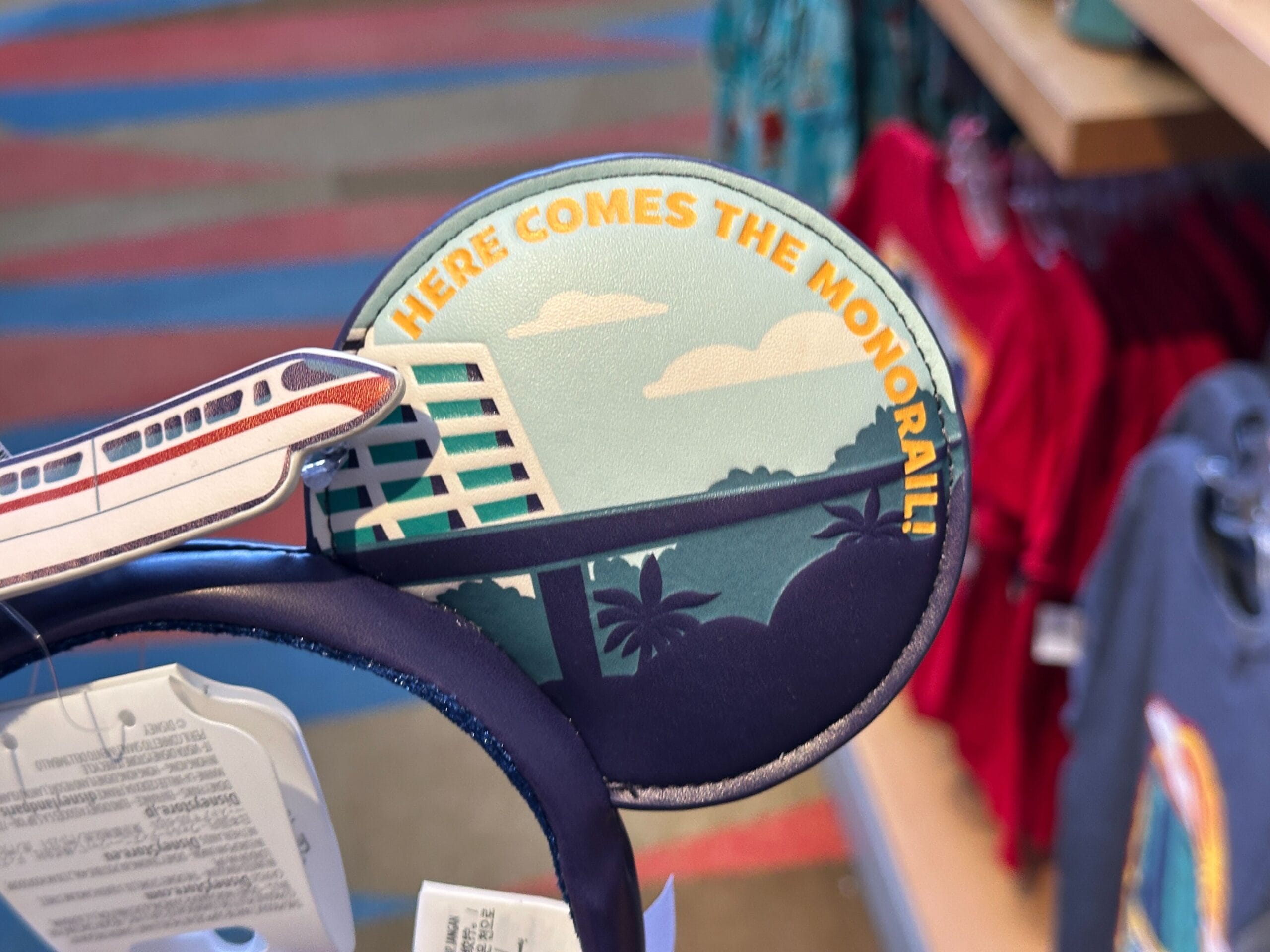 Close-up of a Disney Parks-inspired headband featuring a monorail and "Here Comes The Monorail!" in bold yellow letters.