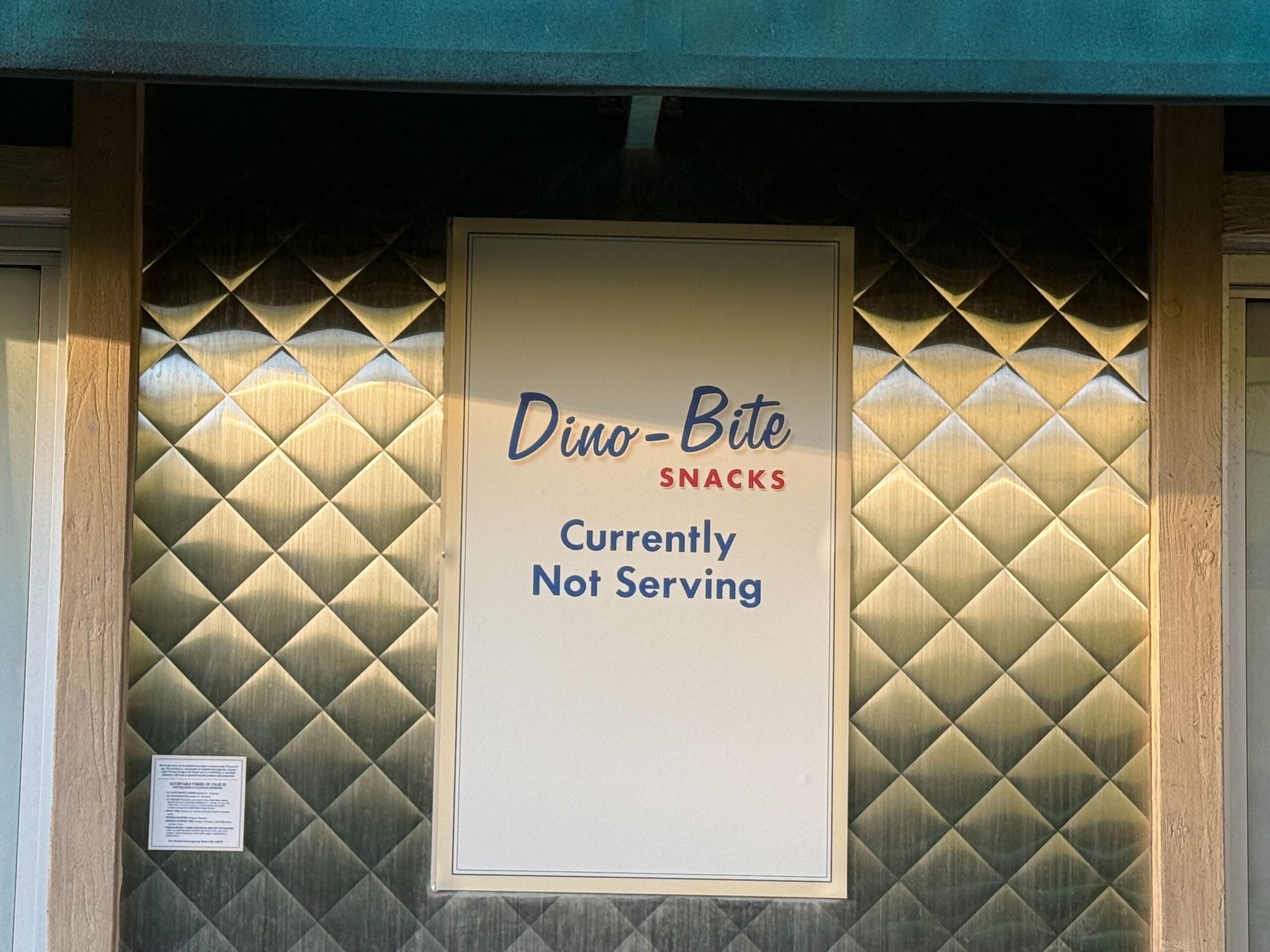 At Disney’s Dino-Bite Snacks, a sign on quilted metallic backing states “Currently Not Serving,” unlike the lively castle eateries.