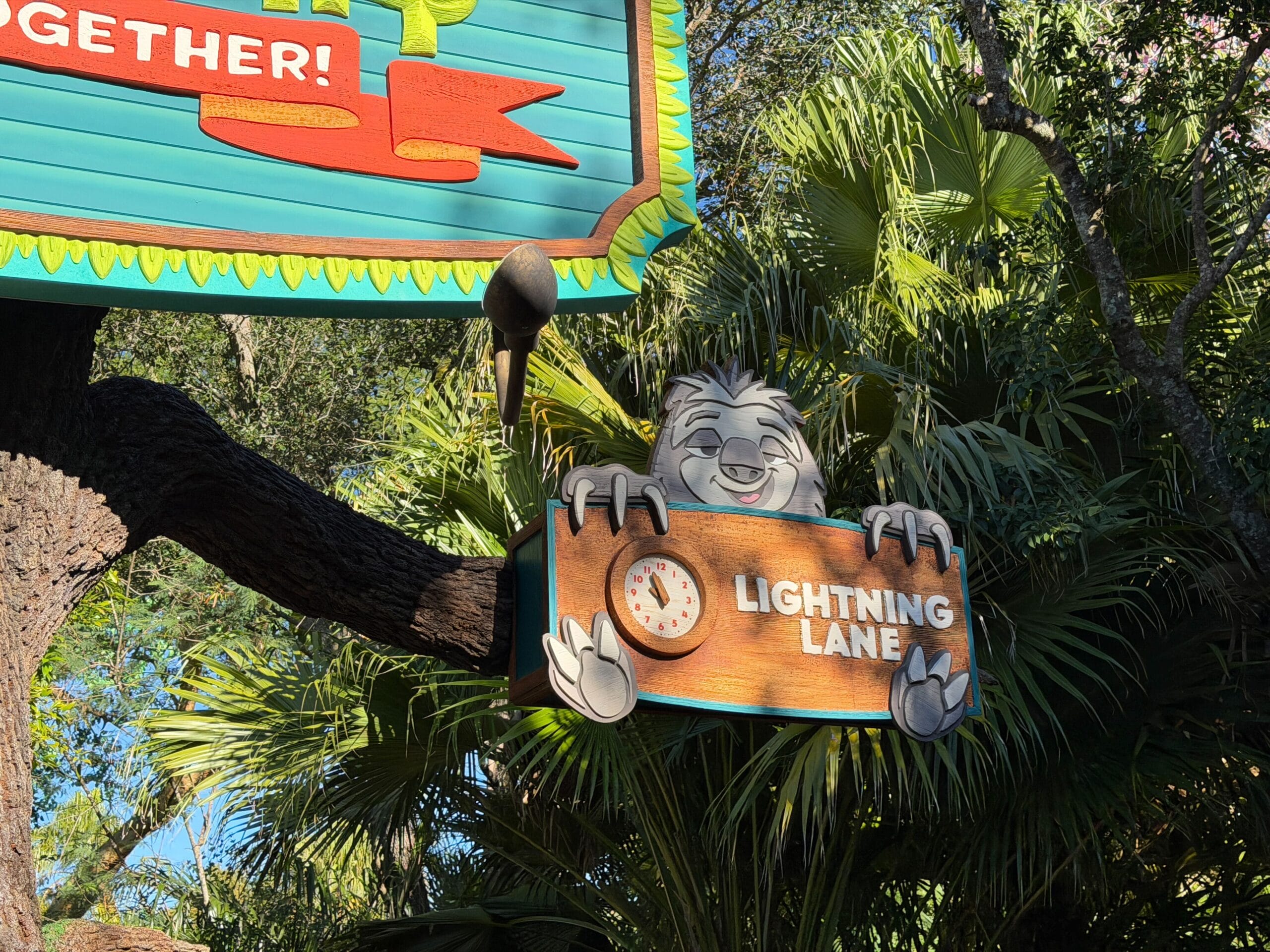 Sign features Zootopia’s smiling sloth holding a “Lightning Lane” sign, with lush Disneyland-style greenery in the background.