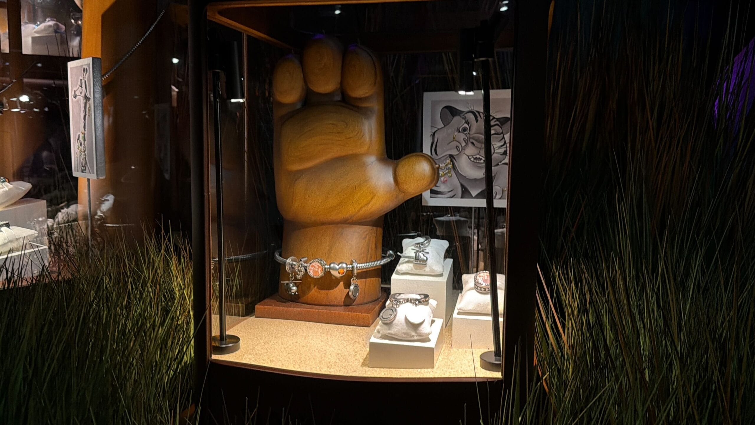 Display case with a large wooden hand sculpture, Disney-themed wristwatches, and sketches, reminiscent of park exhibit decor.