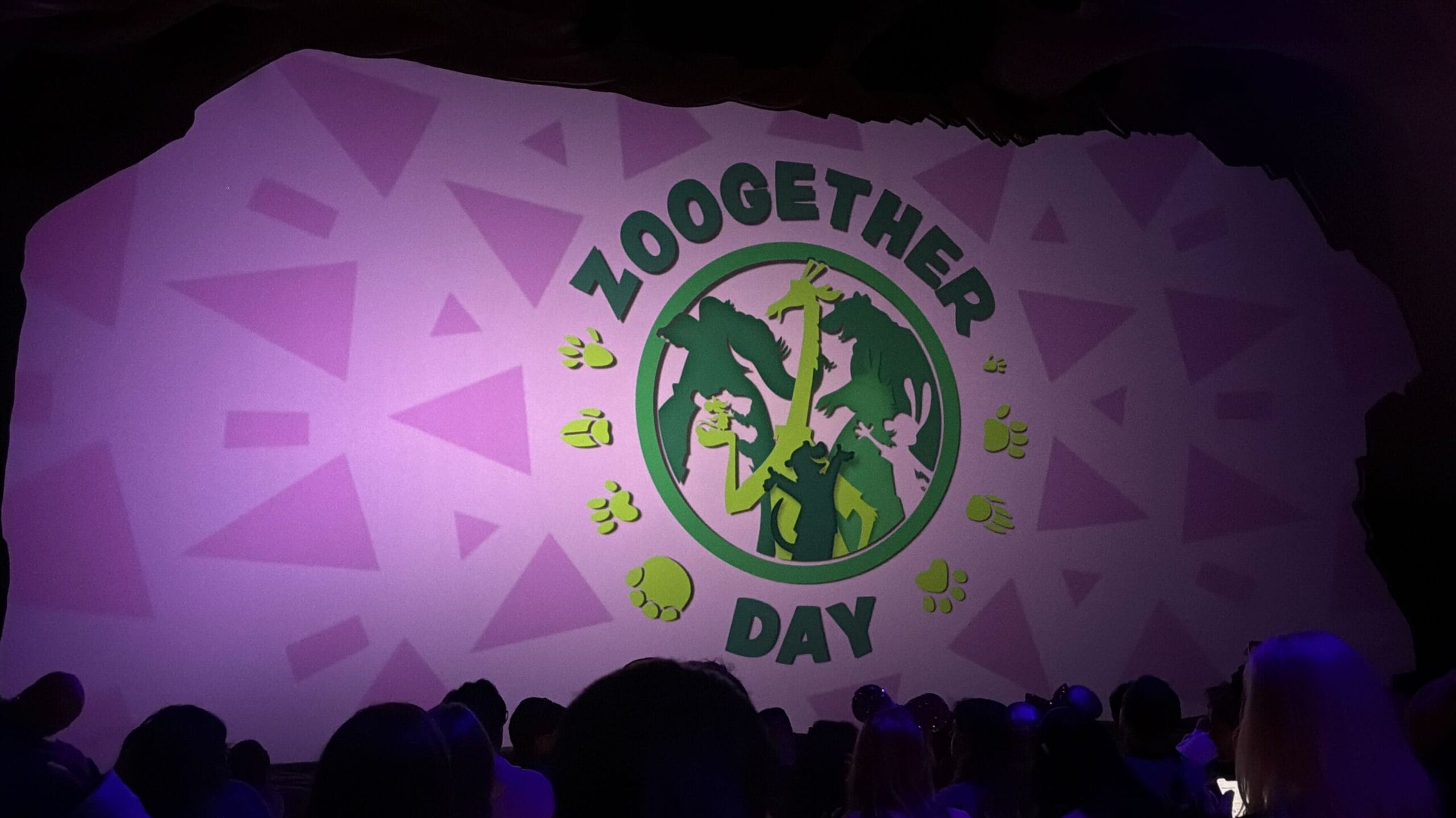 In a dark theater at Animal Kingdom, guests watch Zoogether Day as Zootopia animal silhouettes illuminate the screen.
