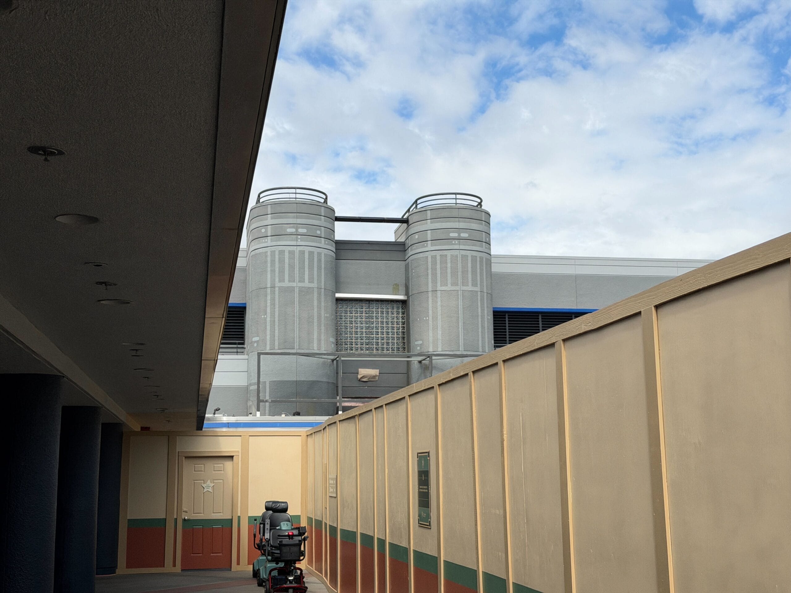 A mobility scooter sits by a construction wall near Star Wars Launch Bay at Hollywood Studios, no Disney castle visible nearby.