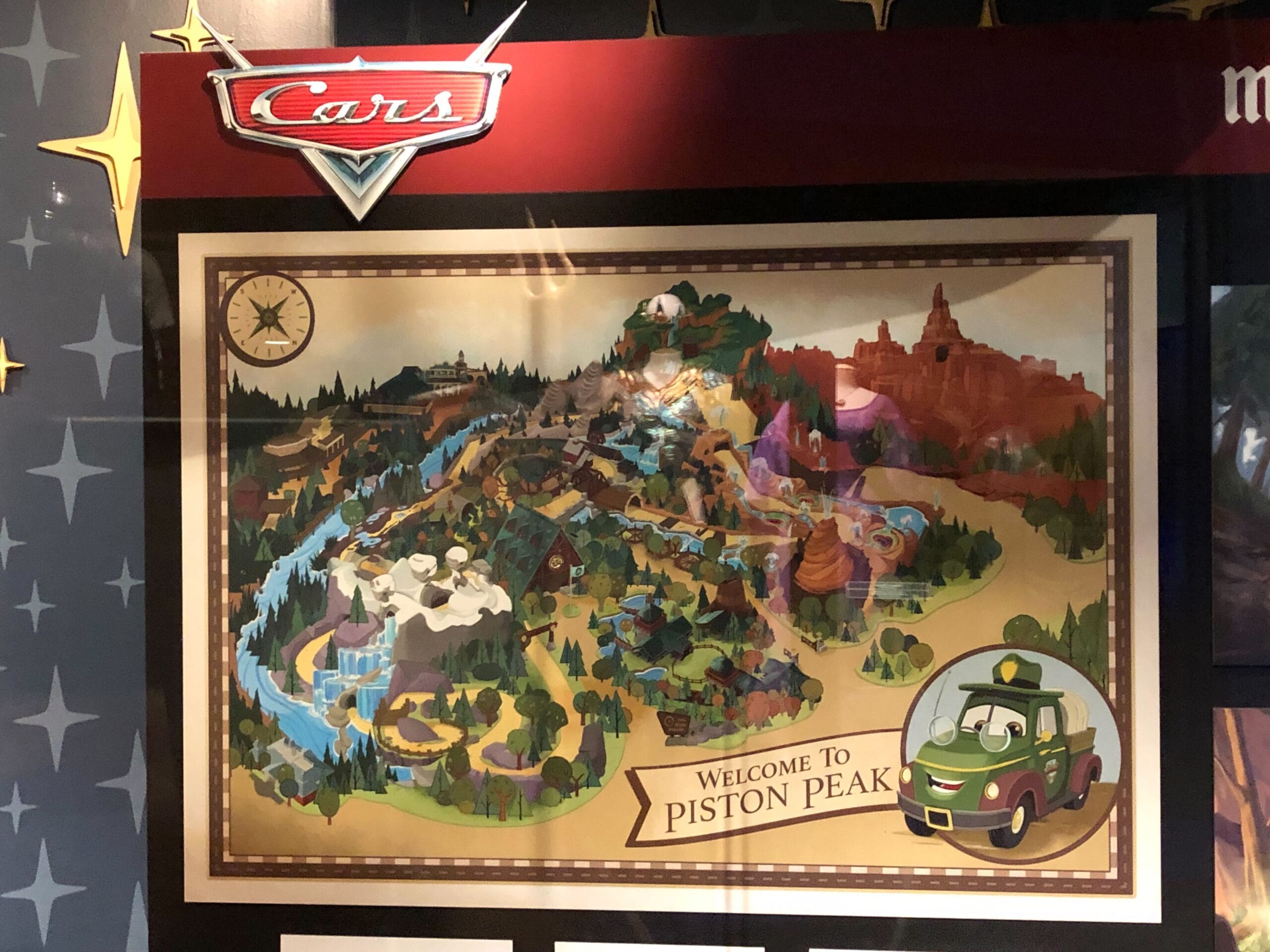A vibrant illustrated map labeled "Welcome to Piston Peak" in Cars Land, highlighting attractions, landscapes, and themed park details.