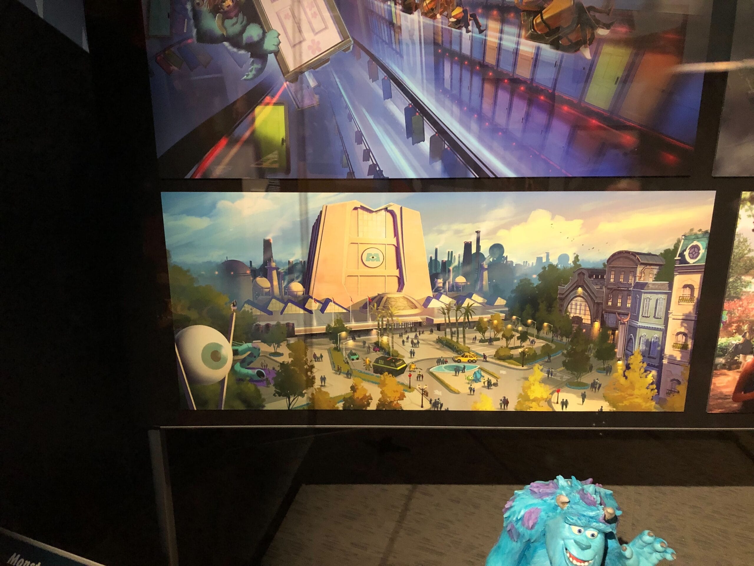 Futuristic campus concept art with students and a green eyeball mascot, echoing Monsters Inc. Coaster at Disney Parks.