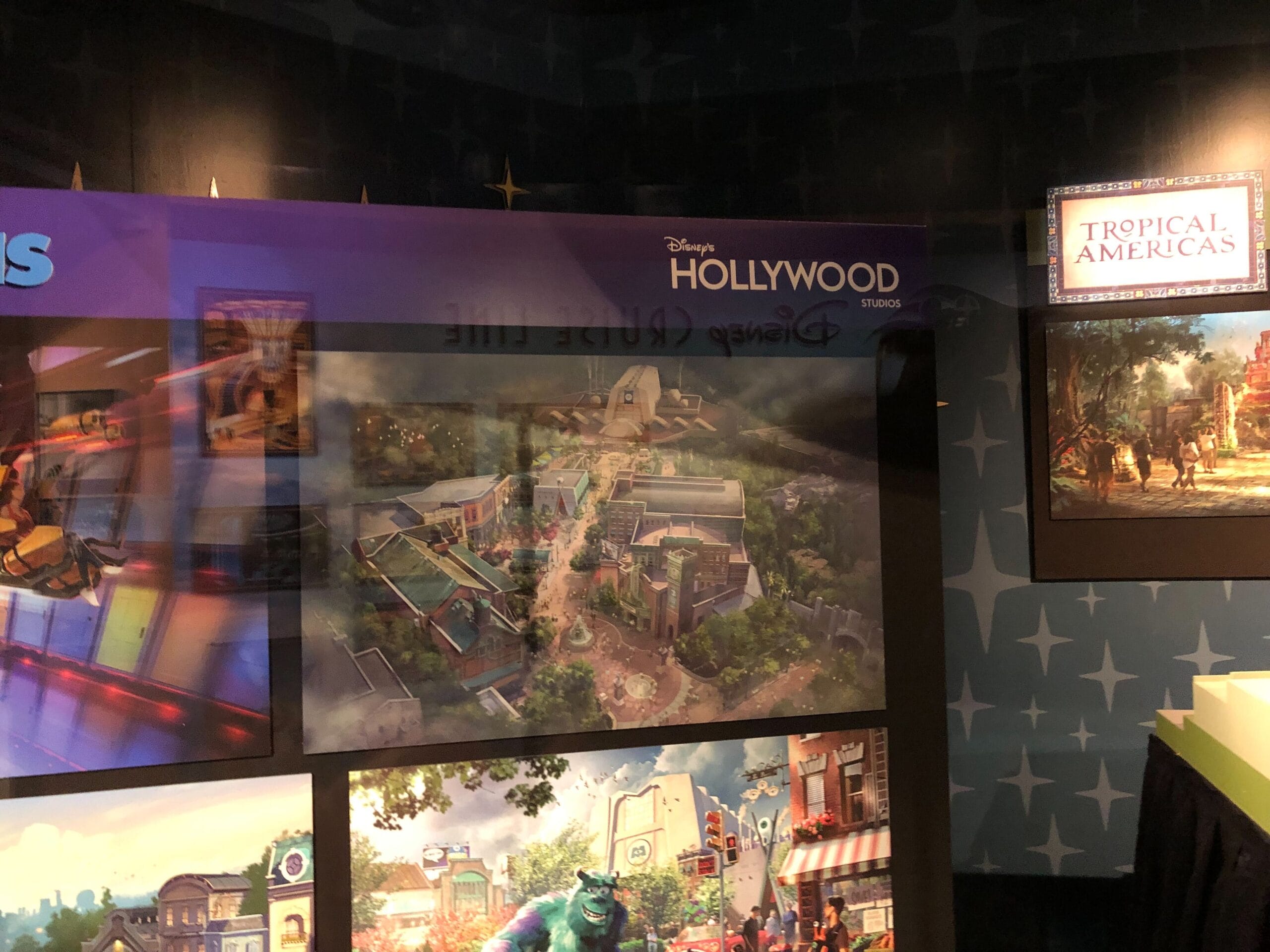 Concept art for Disney’s Animal Kingdom and a "Tropical Americas" sign are displayed on a star-patterned wall, no castle shown.
