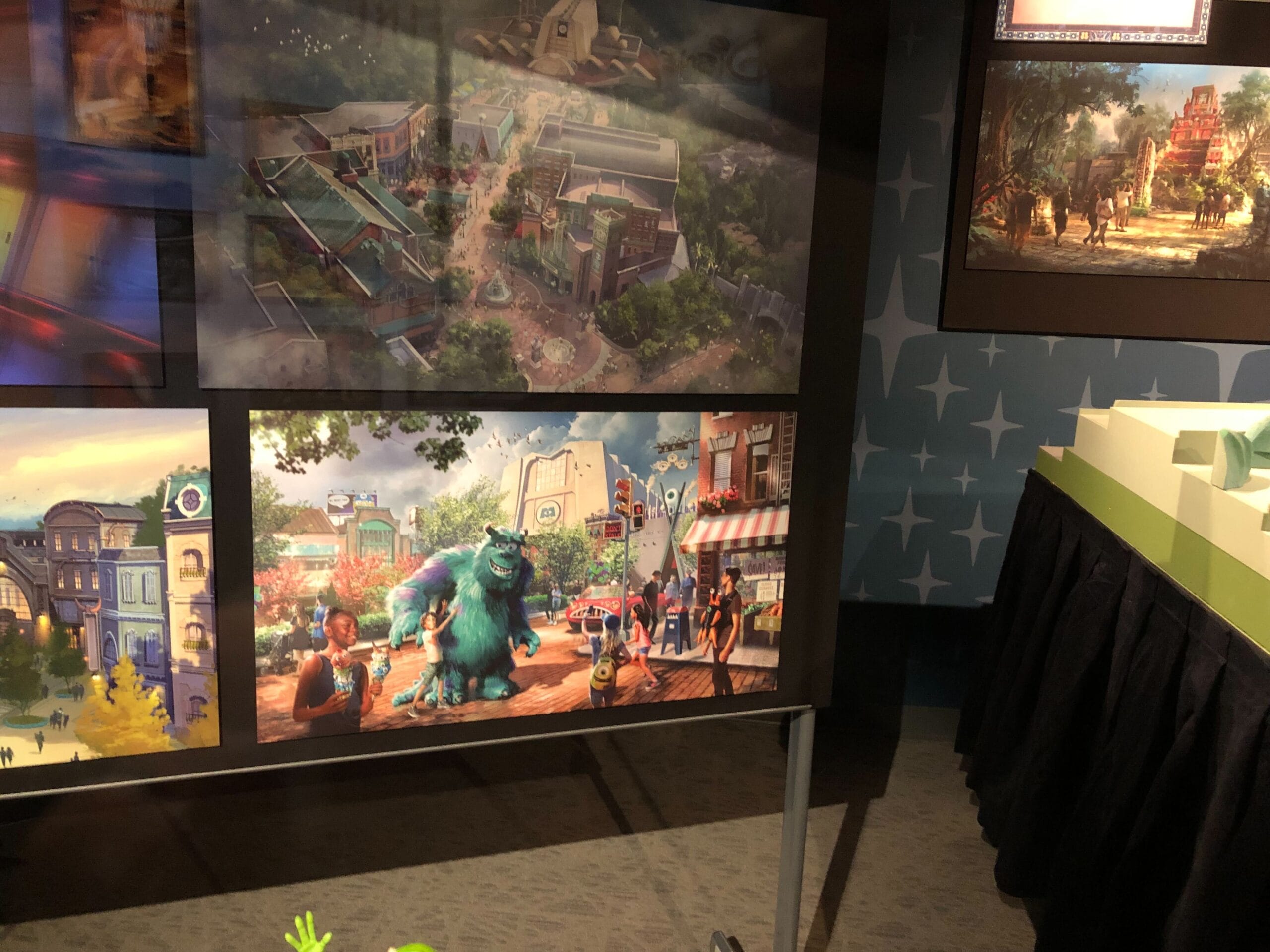 Art display of Disney Park concept art, featuring a Monsters Inc. Coaster in a vibrant city, reminiscent of Pixar Pier at Disneyland.