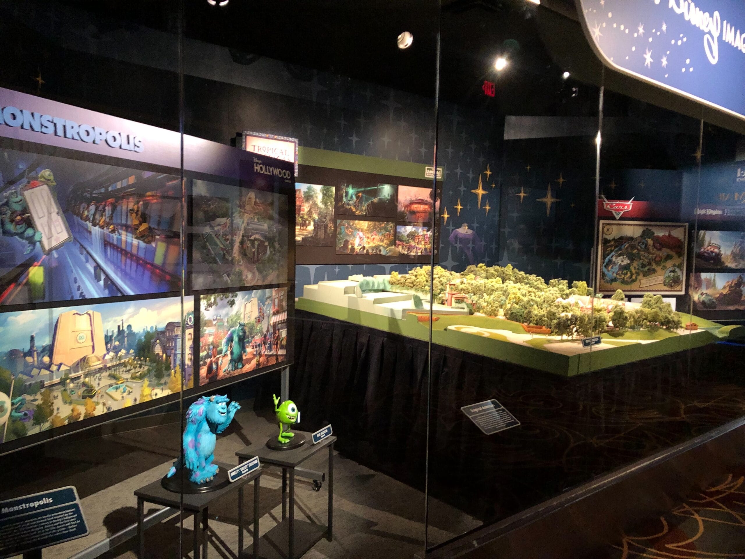 Exhibit displays Monsters, Inc. models and art with Sulley and Mike, suggesting a possible coaster like those in Disney parks.