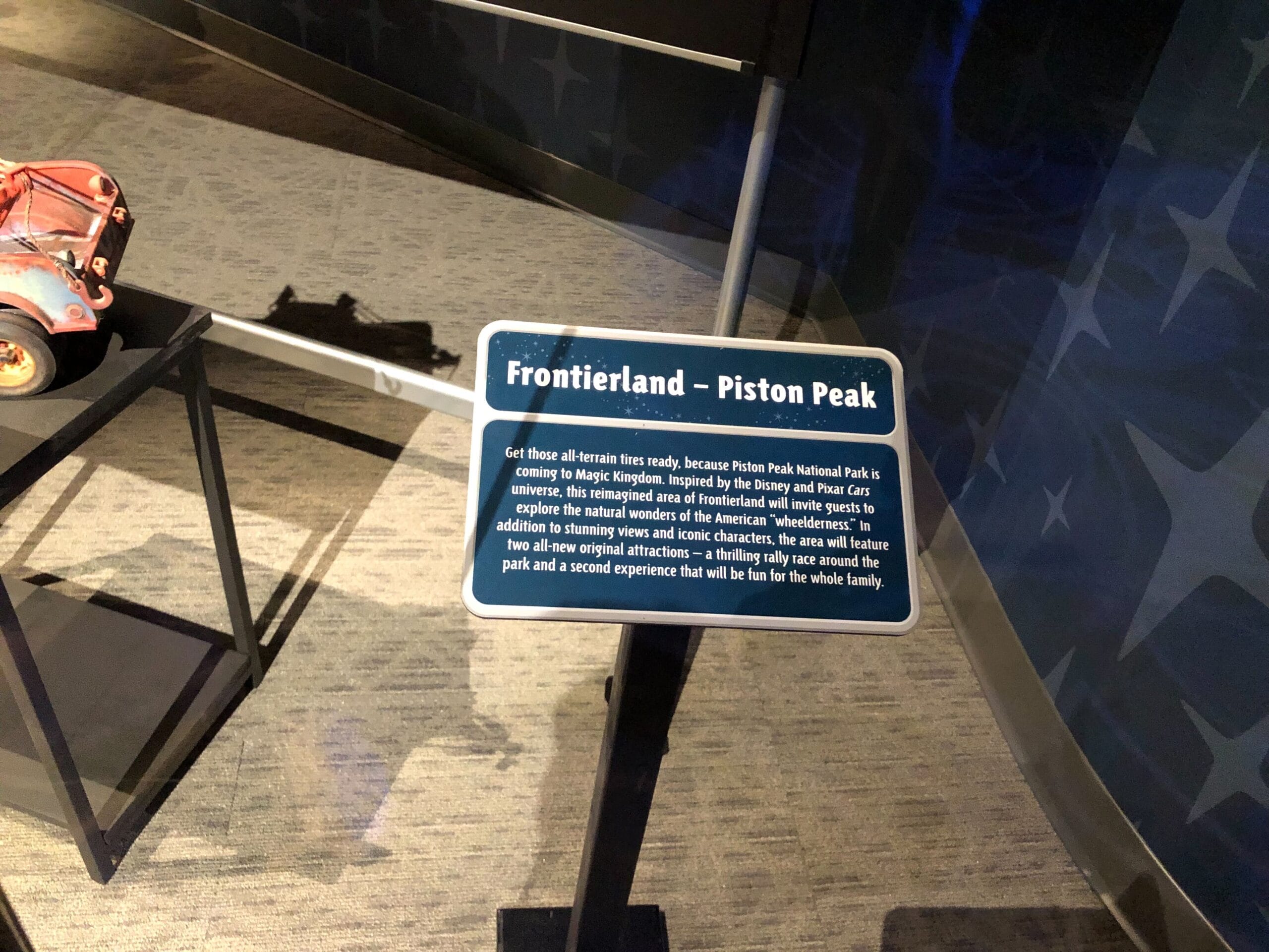 Frontierland – Piston Peak sign, Cars Land-inspired, details a Disney theme park attraction displayed indoors (no castle visible to compare).