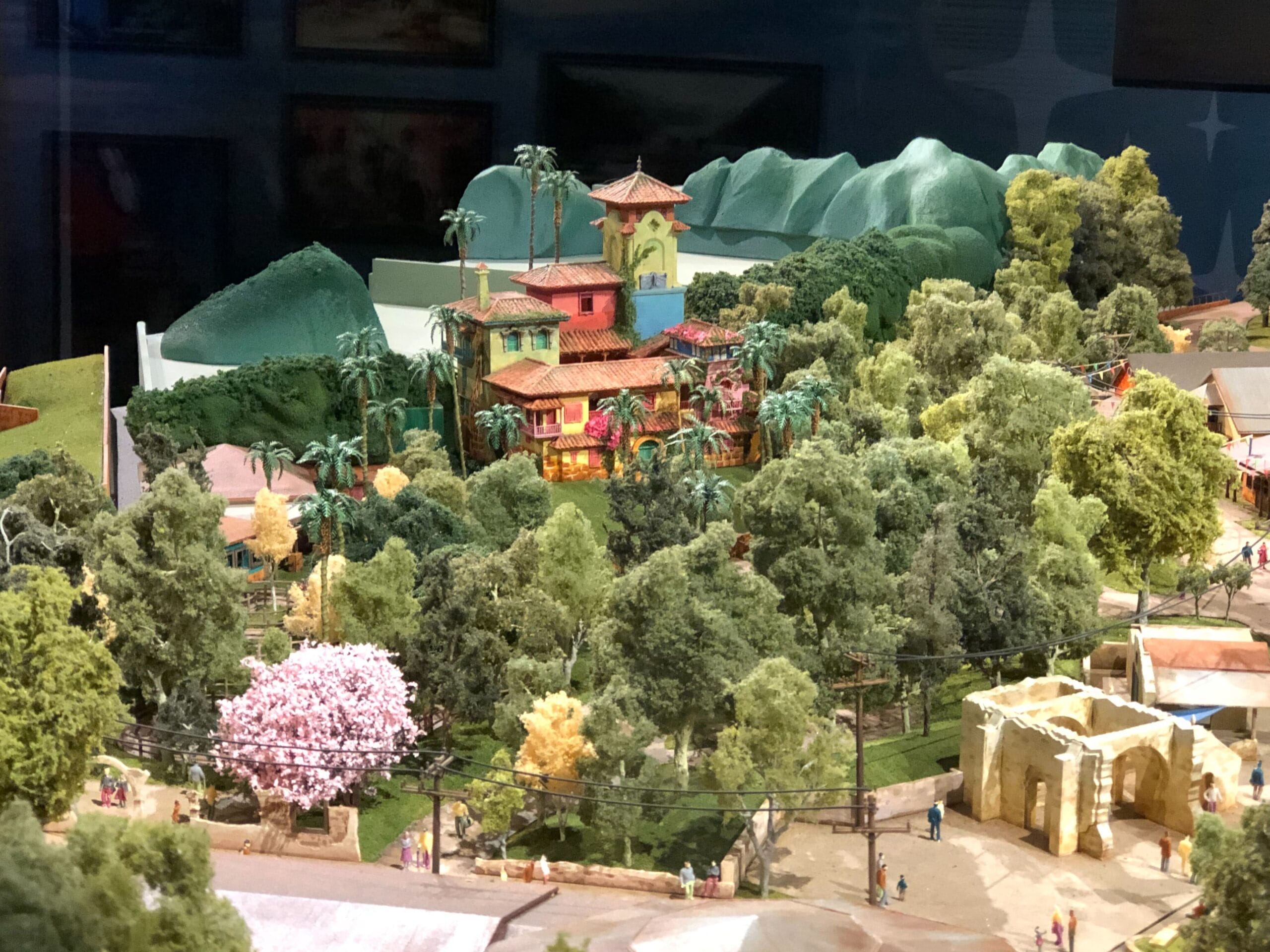 A vibrant model of a tropical villa, reminiscent of Disney’s Animal Kingdom, nestled among lush greenery and rolling hills.
