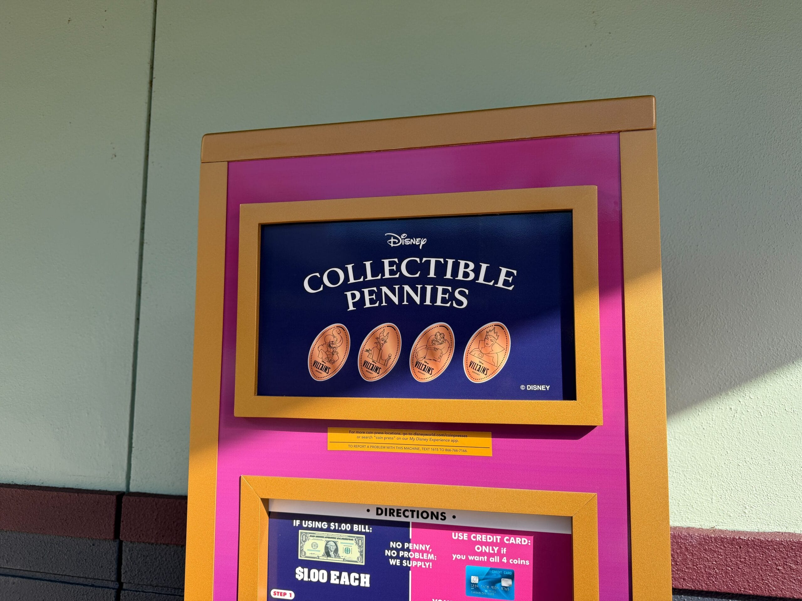 A Disney pressed penny machine at a theme park, with designs and instructions above the slot, like ones found at Disney castles worldwide.