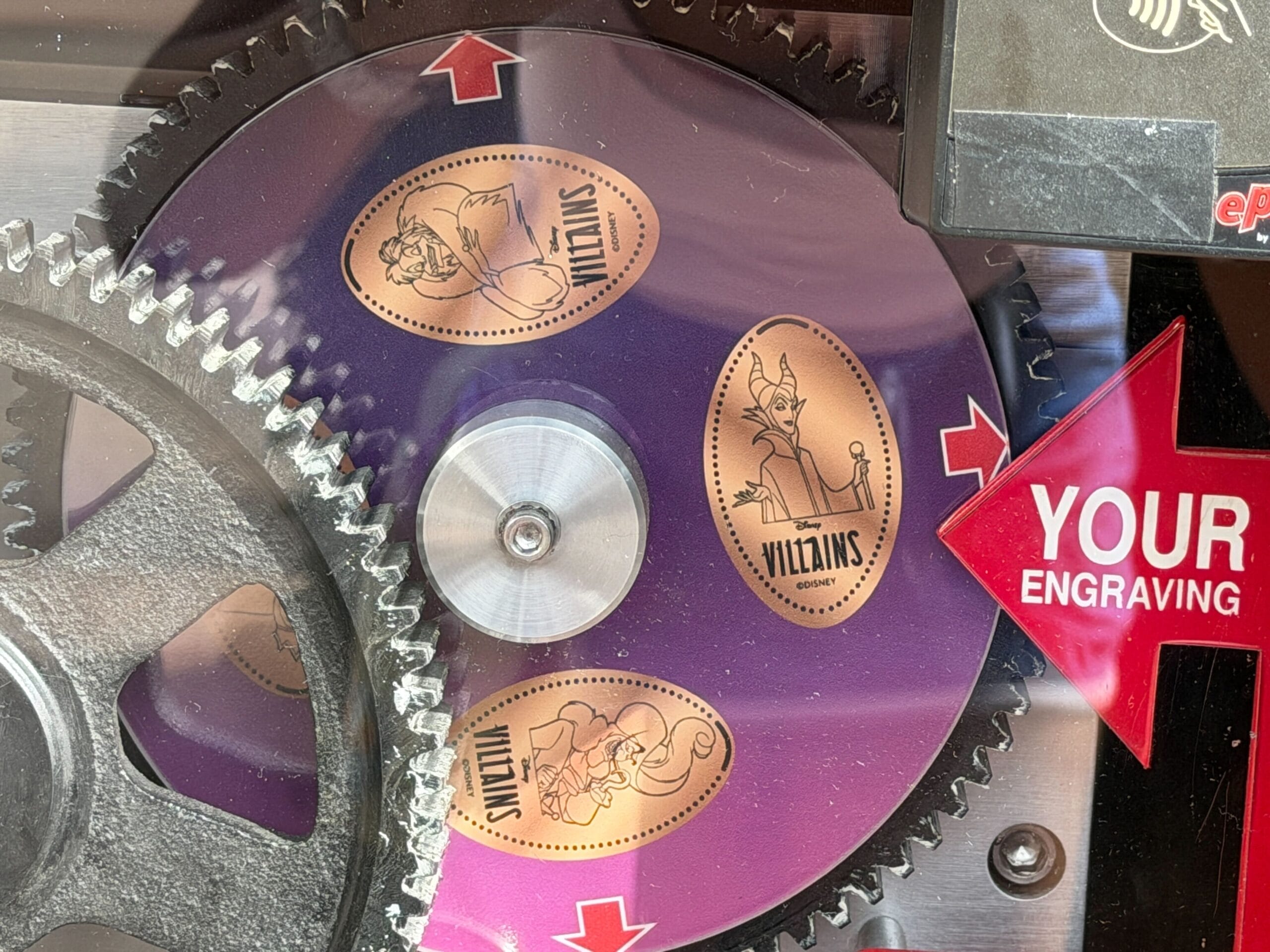 Close-up of pressed penny machine wheel at featuring Disney Villains designs of Cruella de Vil, Maleficent, and Captain Hook.