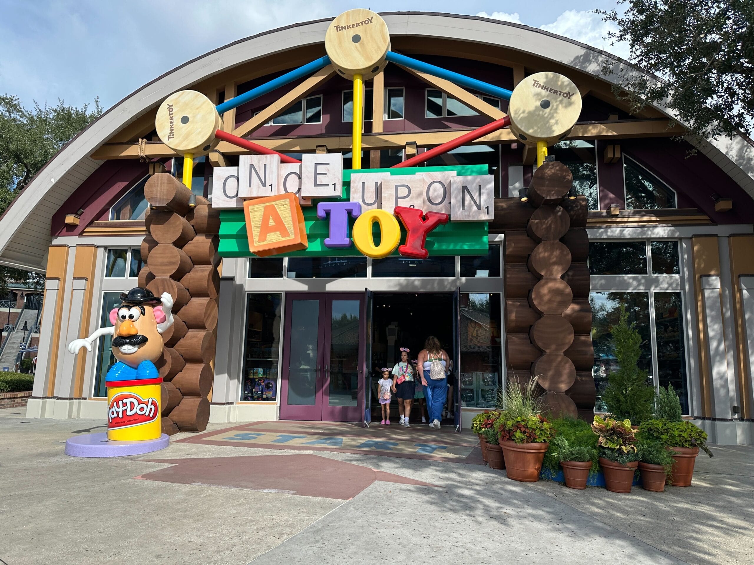 Vibrant entrance to Once Upon a Toy at Disney Springs, featuring a cheerful Mr. Potato Head statue, but no Disney castle views.