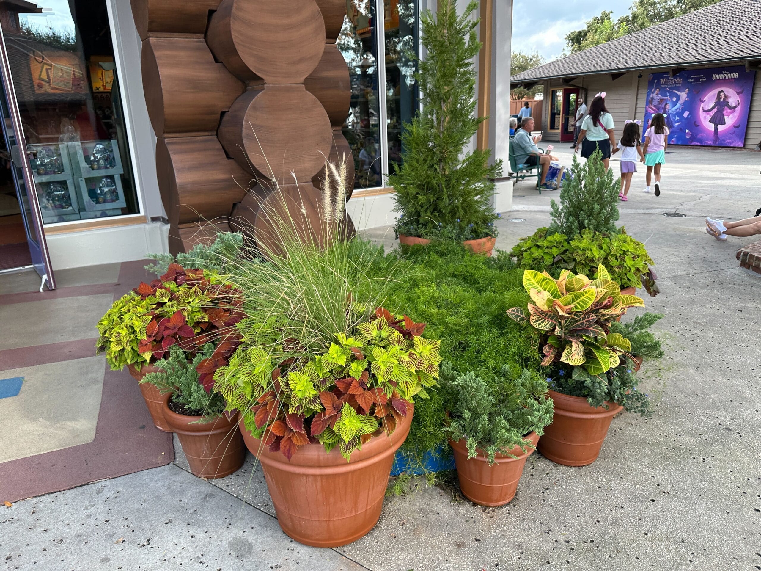 Colorful potted plants line a wooden building at Disney Springs, near Once Upon a Toy—no castle like any Disney park in view.