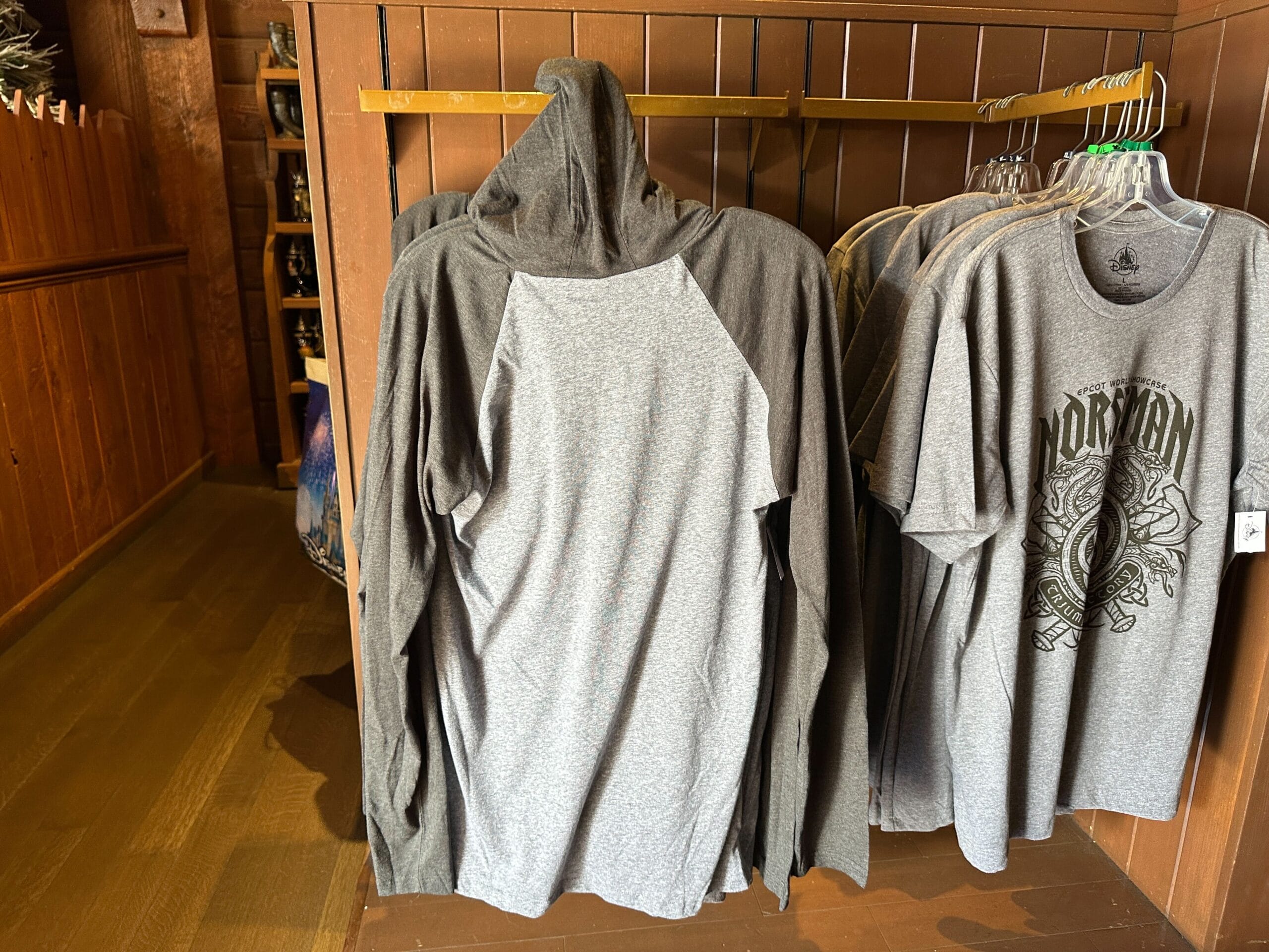 A gray hooded long-sleeve shirt hangs on a rack with gray graphic tees.