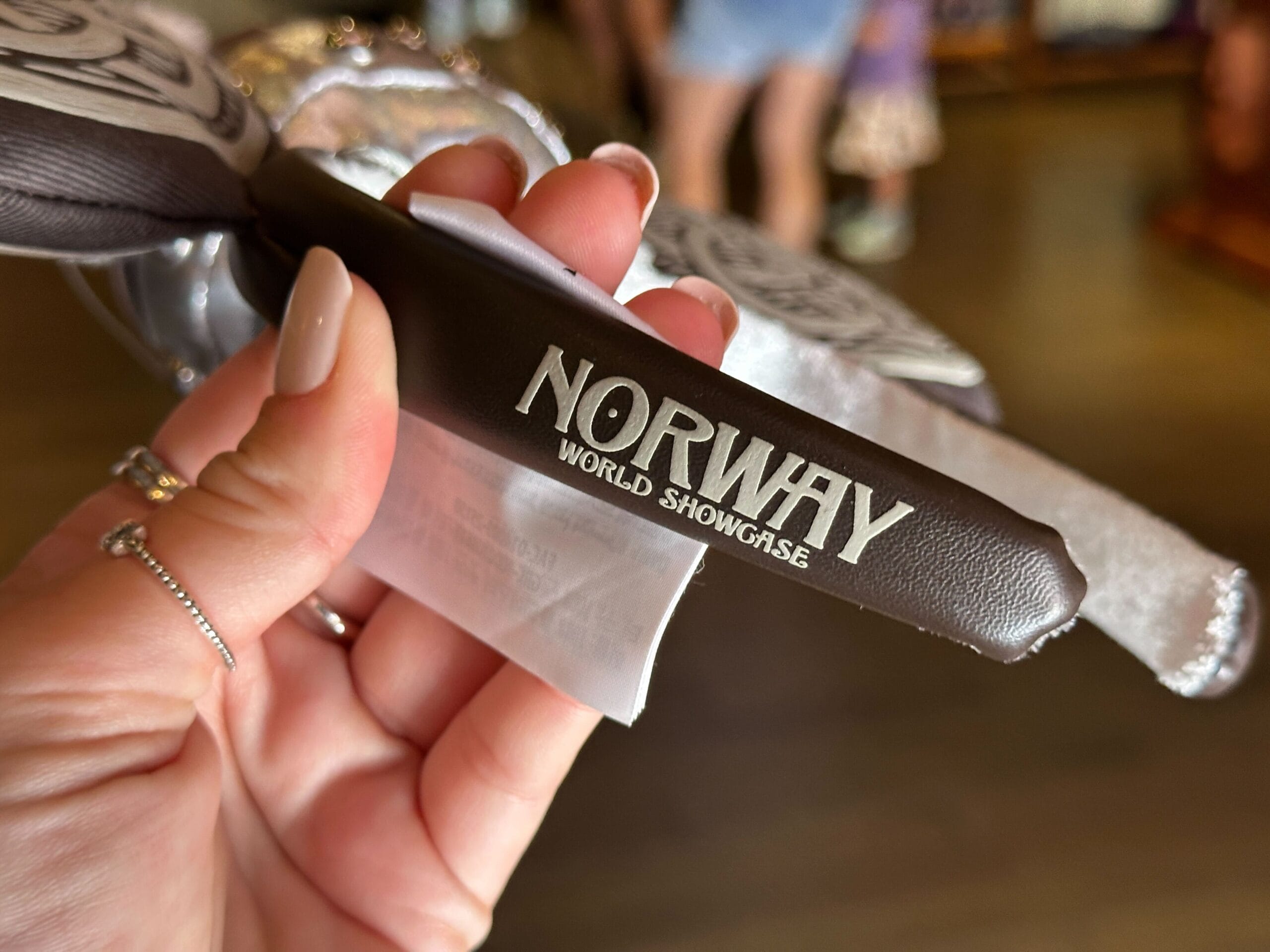 Close-up of a hand holding a dark brown pleather Norway World Showcase headband.