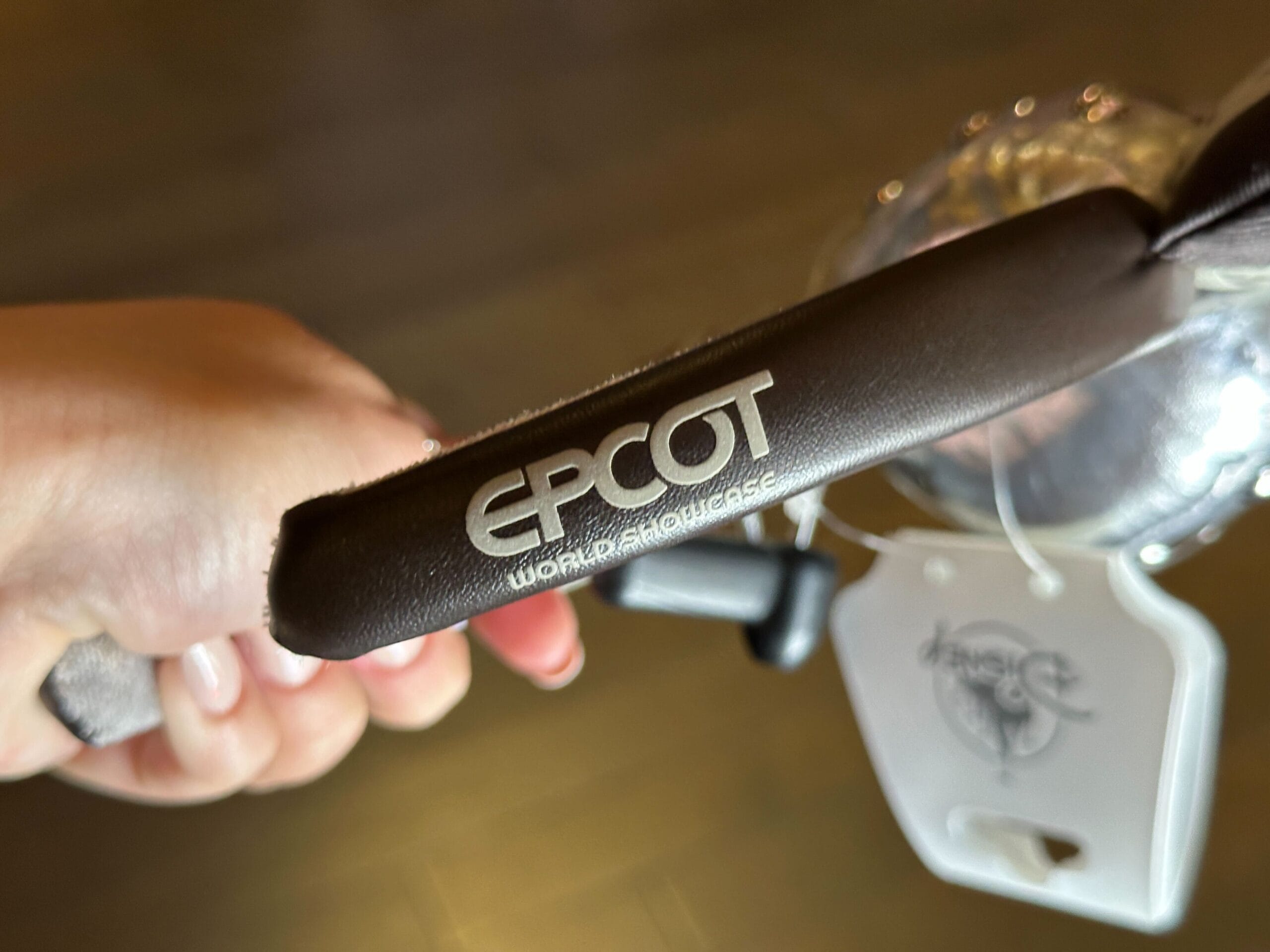 Close-up of a hand holding a dark brown pleather EPCOT World Showcase headband.