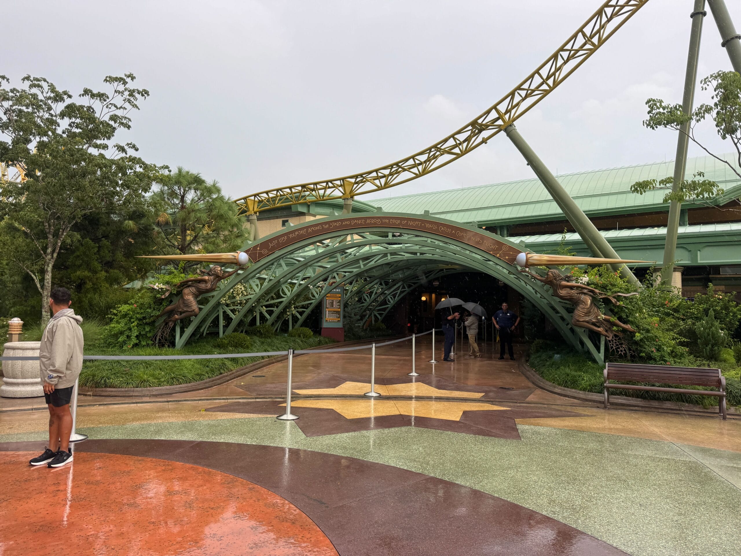 People stand near the entrance arch to Stardust Racers as it officially reopens on a rainy day at Epic Universe.