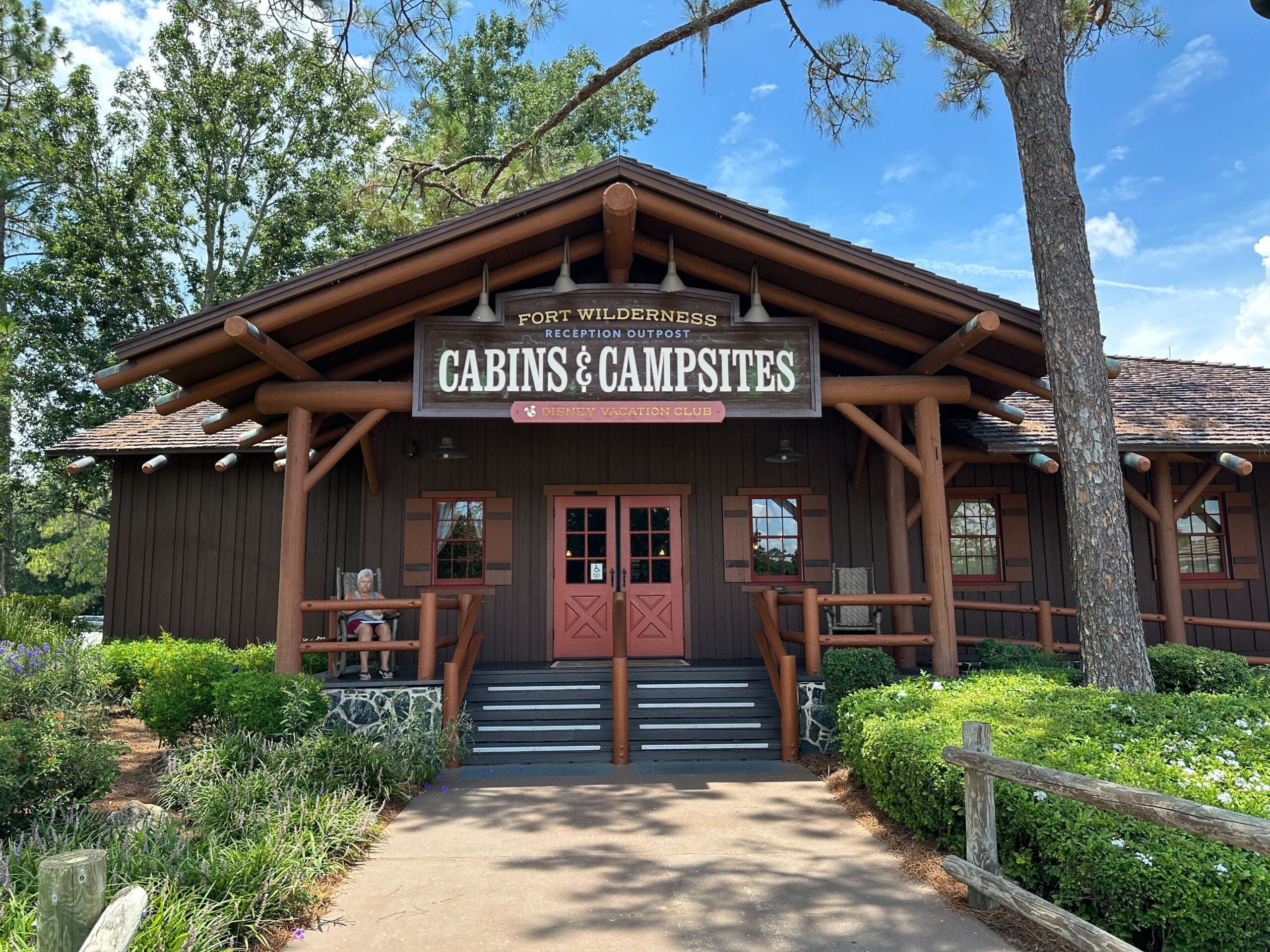 Rustic log cabin with "Cabins & Campsites" sign at Fort Wilderness, nestled among trees—Disney magic far from the iconic park castles.