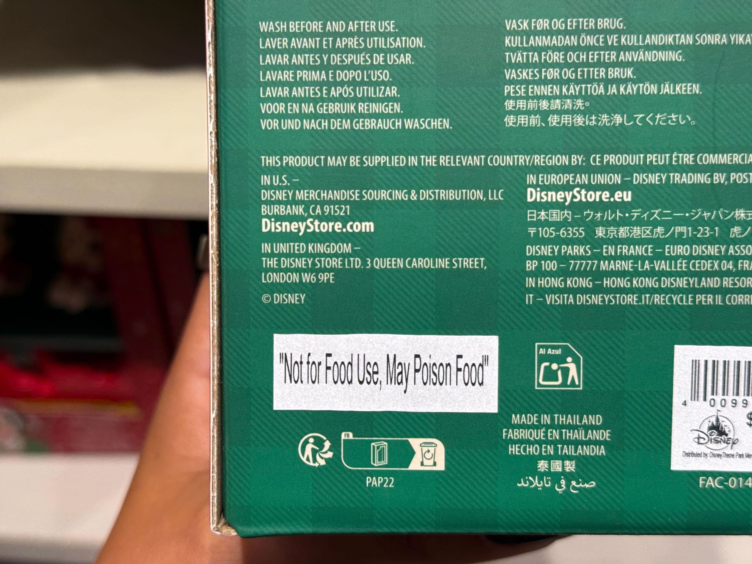 A product box at a Disney park shop displays a multilingual warning: "Not for Food Use, May Poison Food," near themed merchandise.