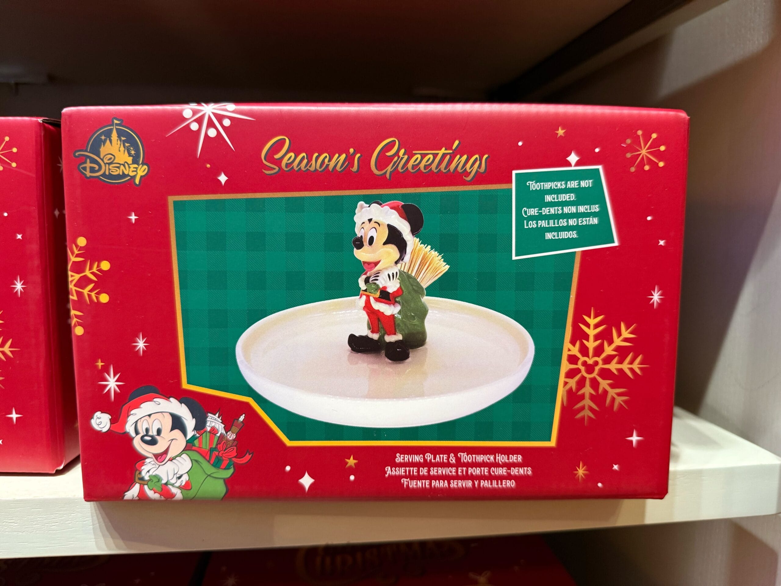 Red Disneyland Resort box holds a Minnie Mouse platter and toothpick holder; festive Christmas merch evokes classic Disney park style.