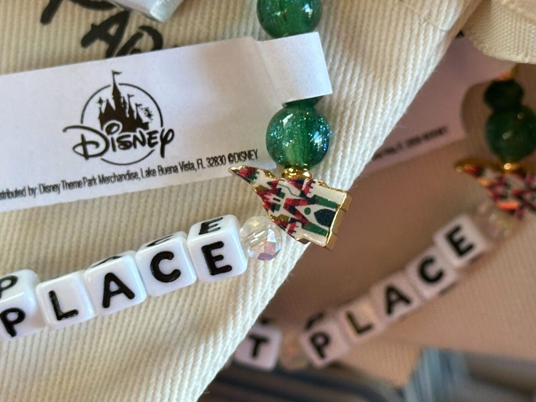 Close-up of beaded keychains with "1ST PLACE" letter beads and a Disney tag, similar to souvenir charms sold at Disney parks worldwide.