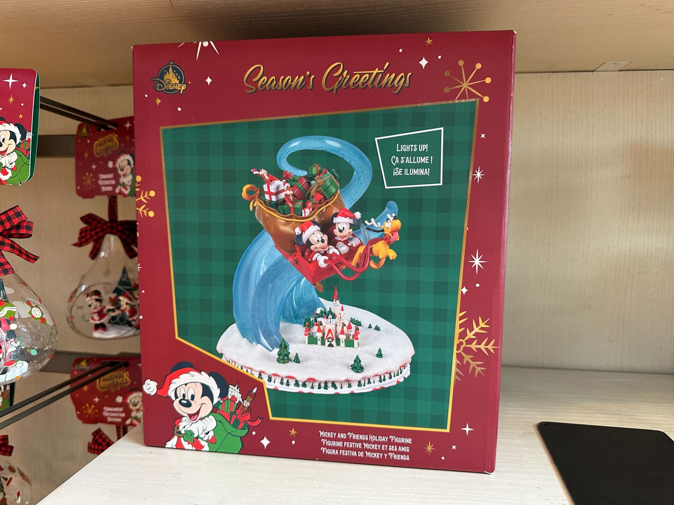 Box featuring Mickey, Minnie, and friends in festive outfits on a sleigh, "Season’s Greetings" above; evokes Disney park holiday spirit.