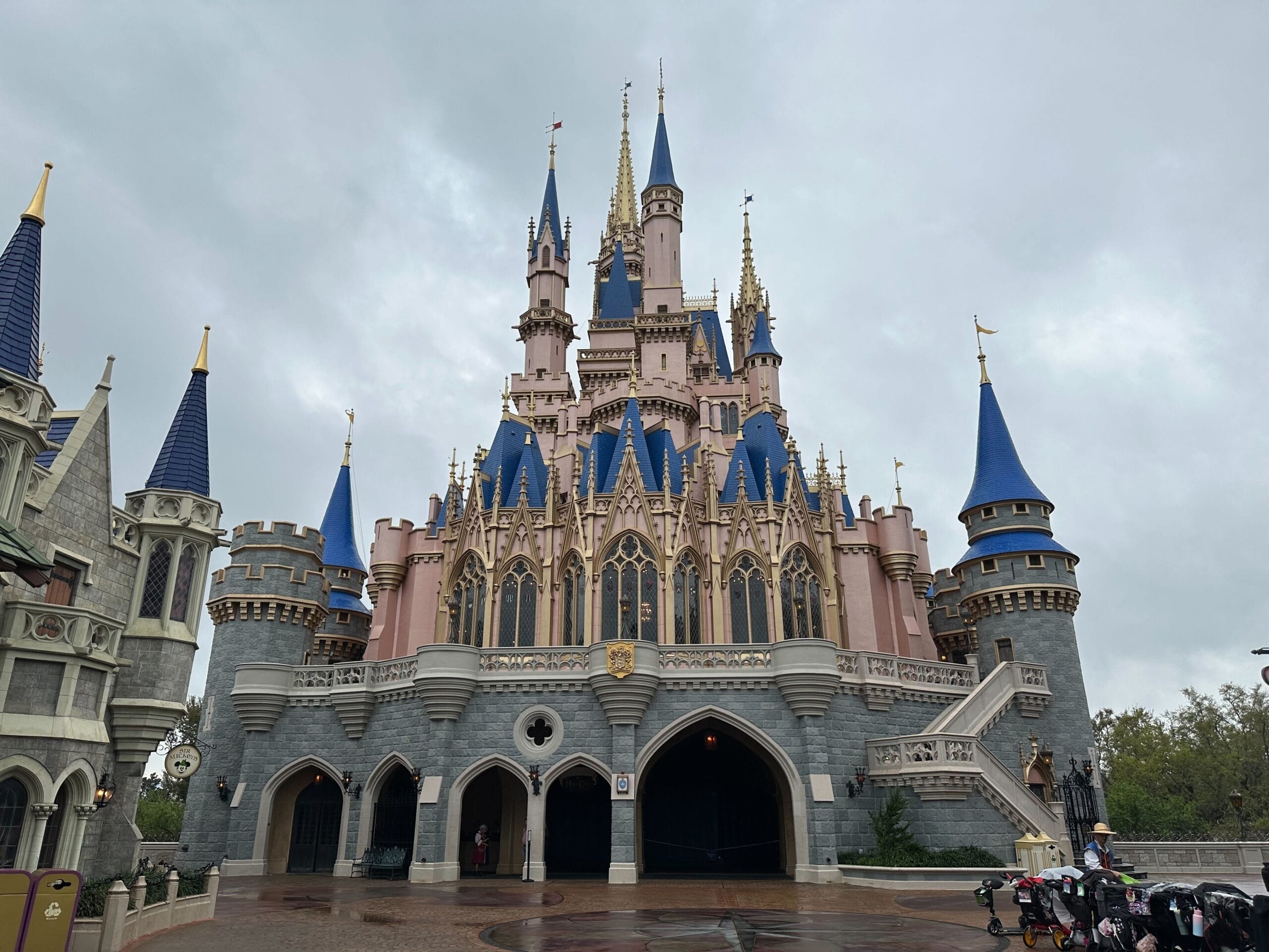 Cinderella Castle at Disney World on a cloudy day, wet pavement gleaming.