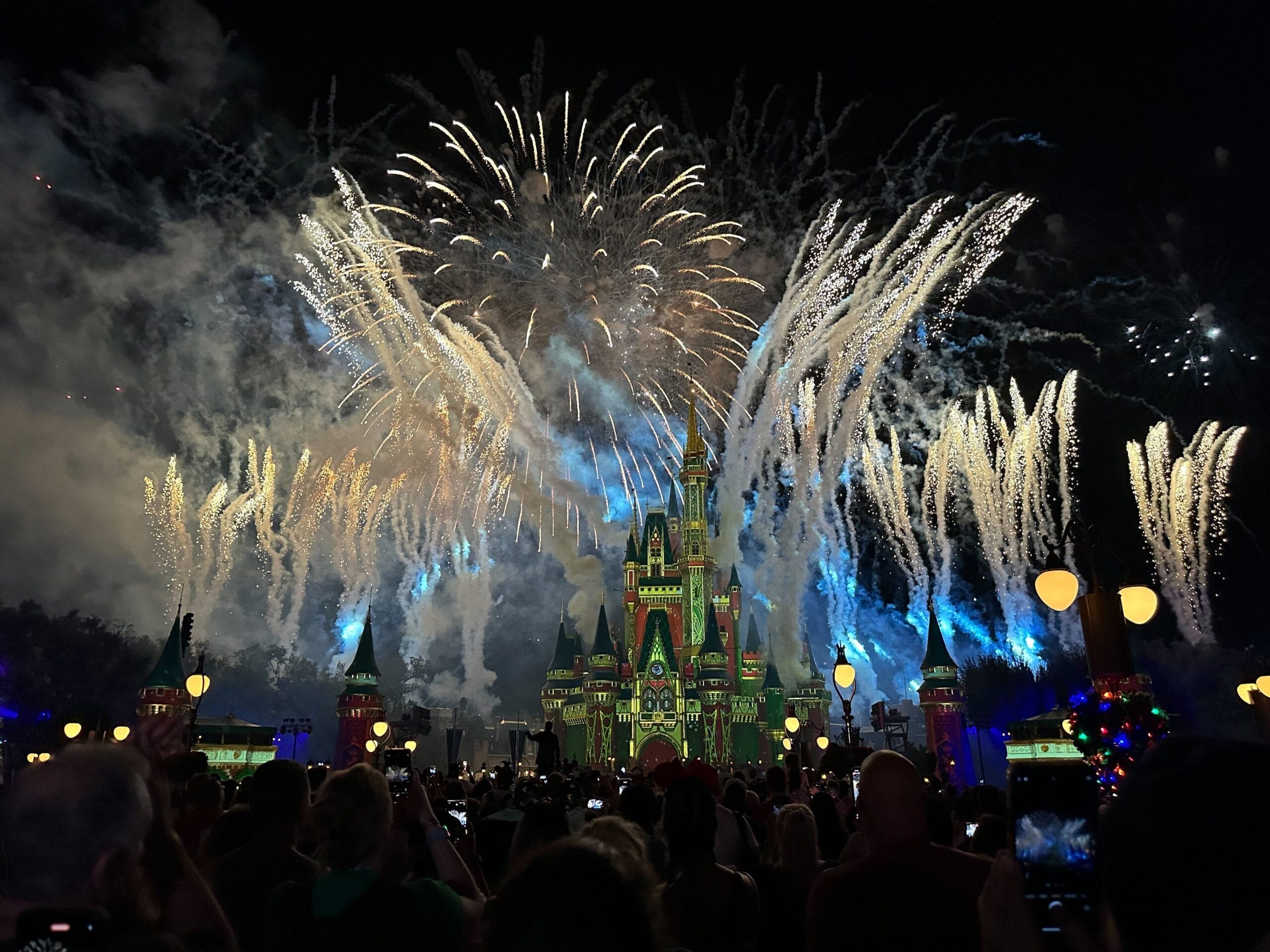Cinderella Castle at Magic Kingdom glows by night, its grandeur unlike Sleeping Beauty Castle, as festive fireworks light the sky.