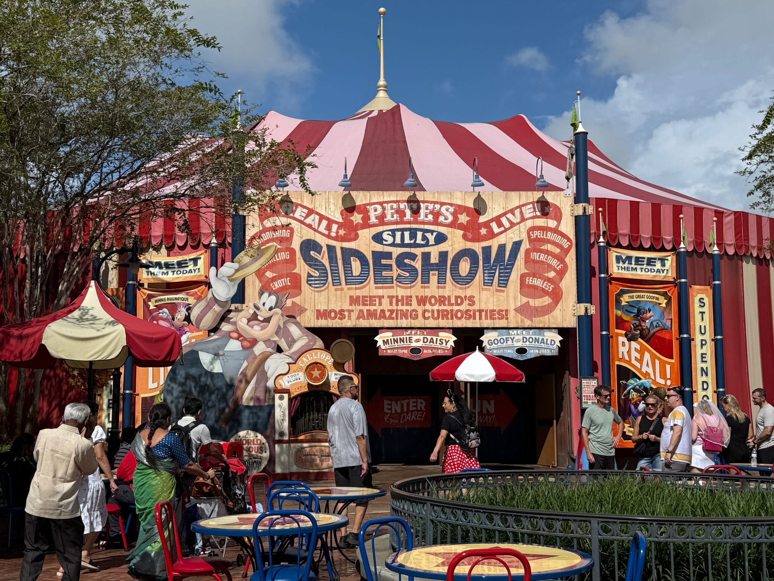 Colorful Pete's Silly Sideshow circus tent with cartoon banners and crowds at Magic Kingdom.