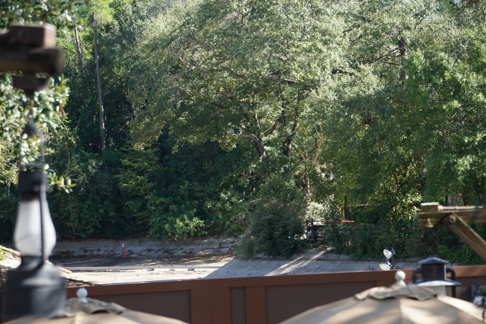 A dry, empty riverbed in a lush, tree-filled Disney park setting, shaded by umbrellas—no castle visible to compare.