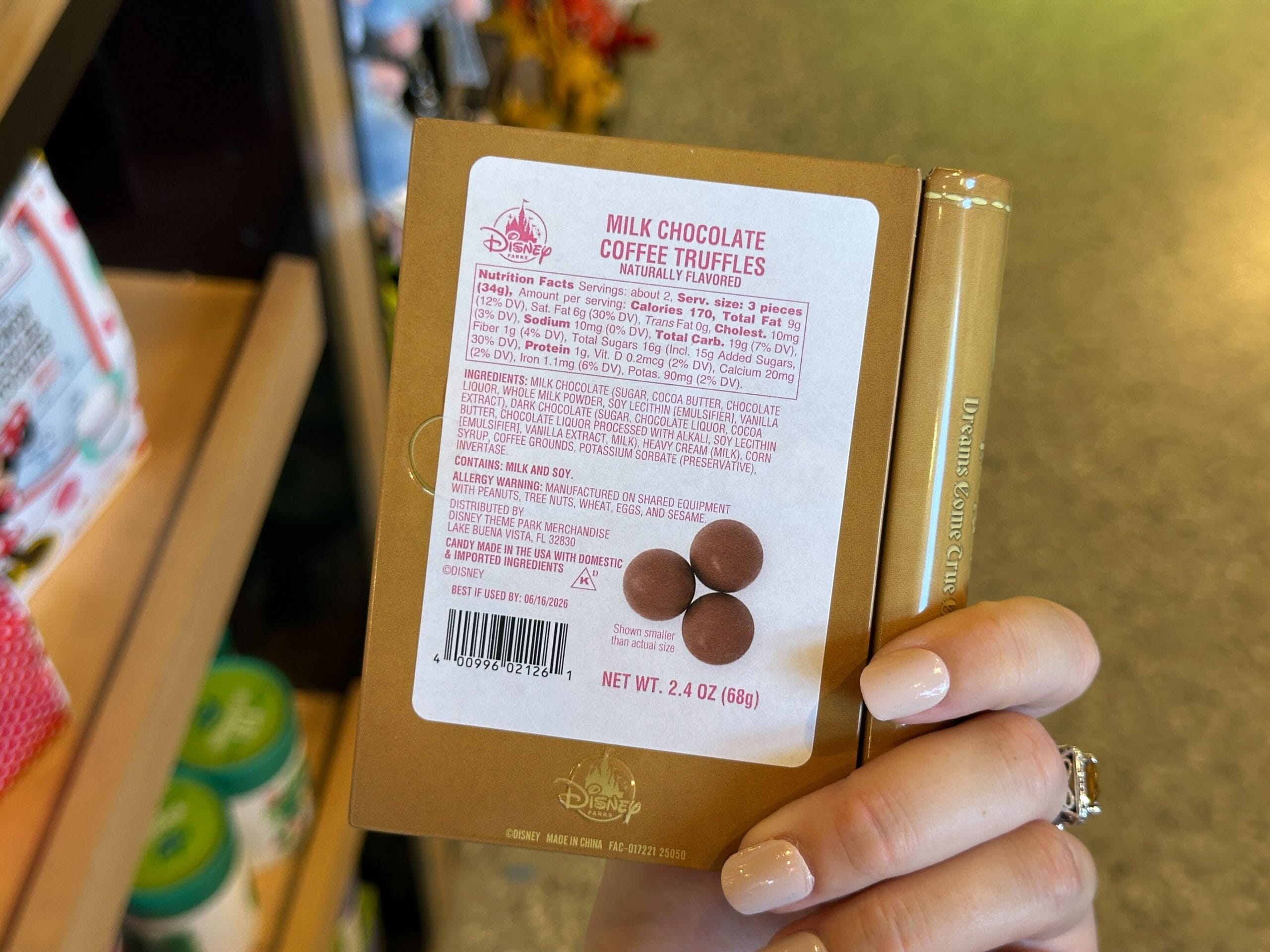 A hand holds Disney Milk Chocolate Coffee Truffles in a box, with the ingredients and nutrition label visible, reminiscent of park treats.