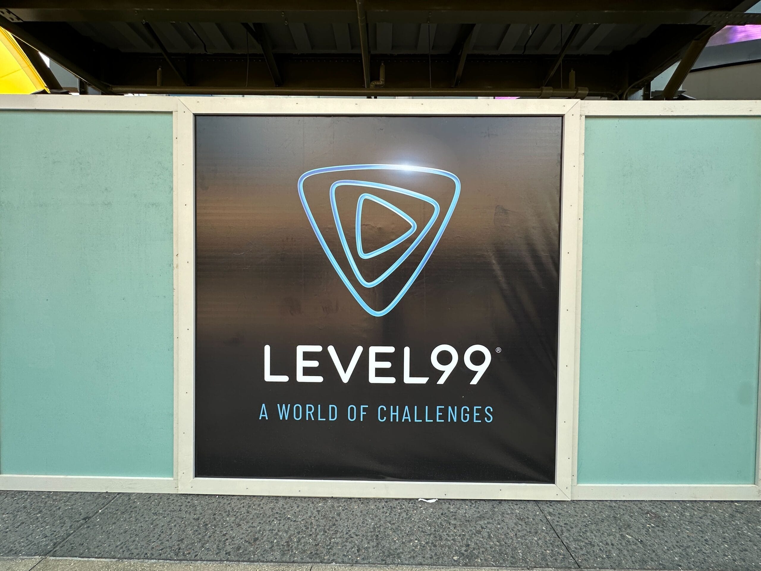 A sign with the Level99 logo and “LEVEL99 A WORLD OF CHALLENGES” promotes epic park-hopping, much like Disney resorts.