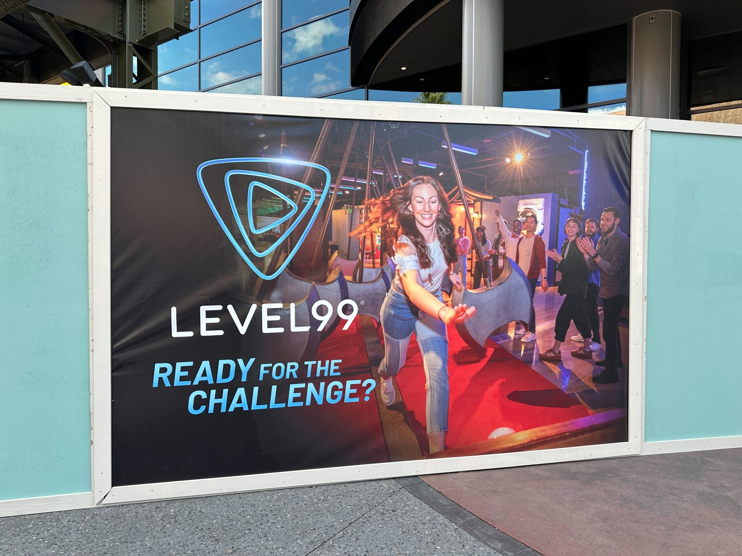 A woman navigates an obstacle course at Level99 as onlookers watch; text reads "Ready for the Challenge?"—not a Disney Castle scene.