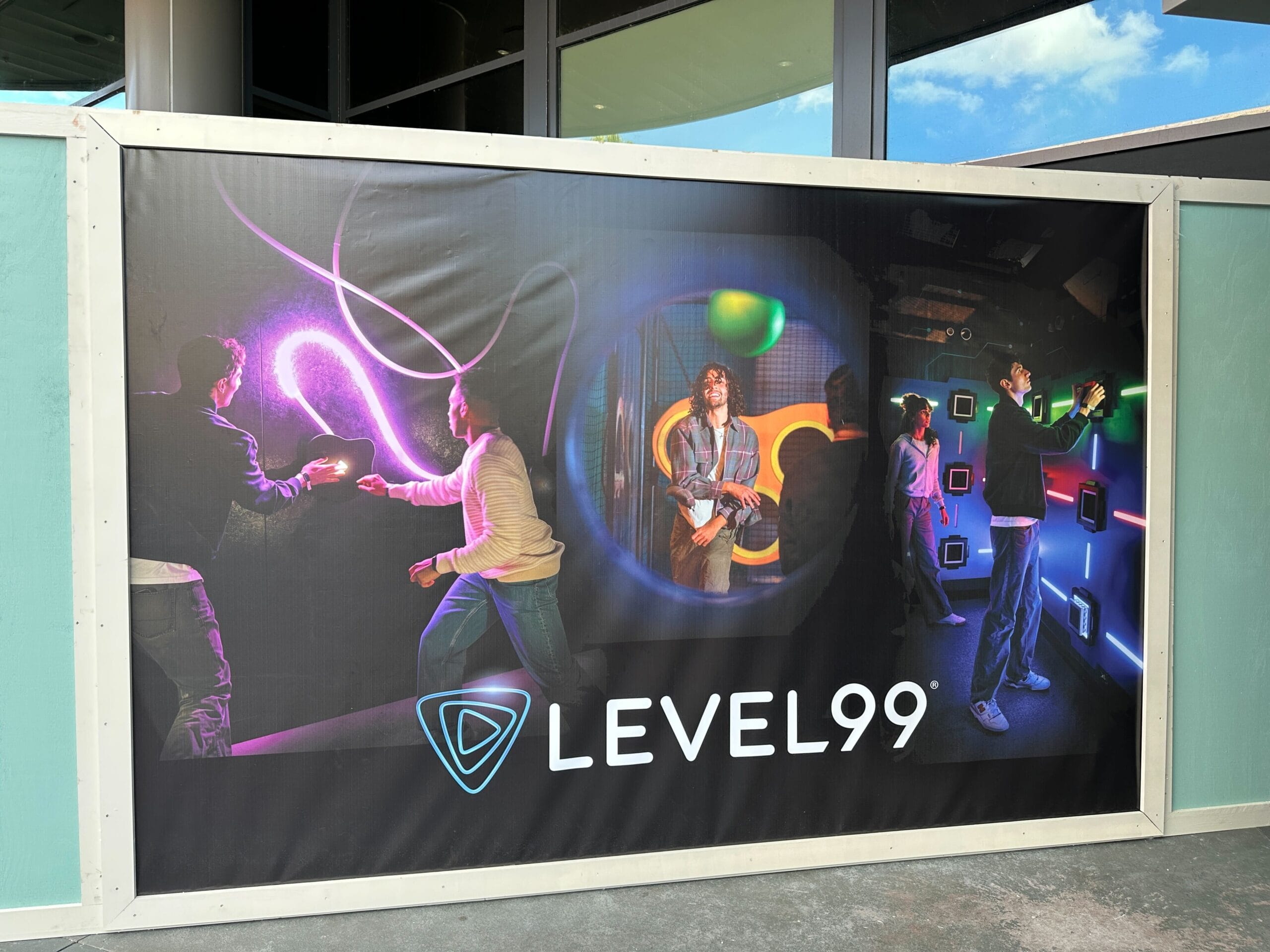 A LEVEL99 banner by glowing arcade games, with guests enjoying a vibrant, futuristic vibe unlike any Disney park castle scene.