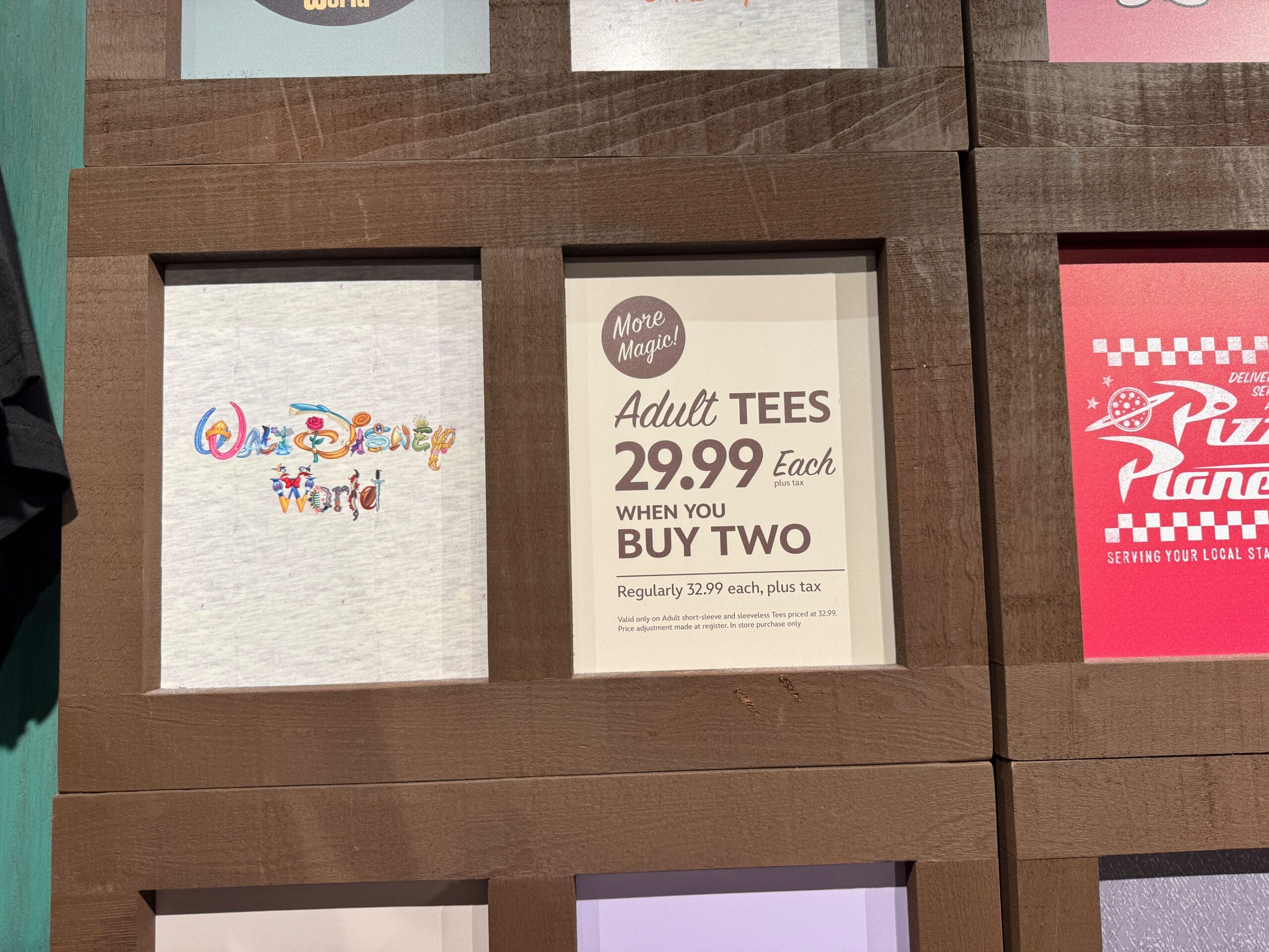 Sign advertising adult tees for $29.99 each when you buy two, with regular price listed as $32.99 each, plus tax.