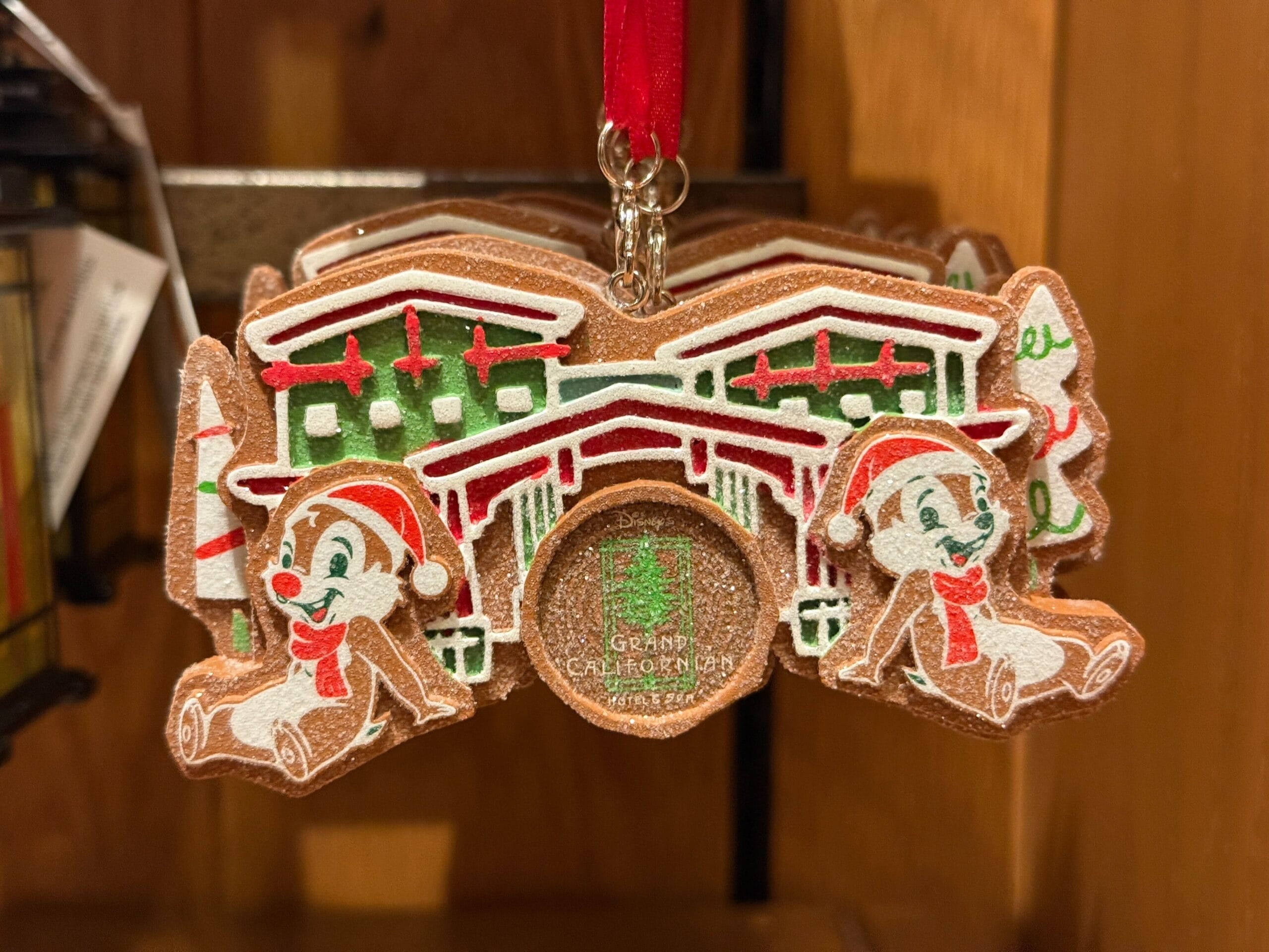 Two Disney chipmunks in Santa hats sit by a Grand Californian holiday display, surrounded by festive decorations at the resort.