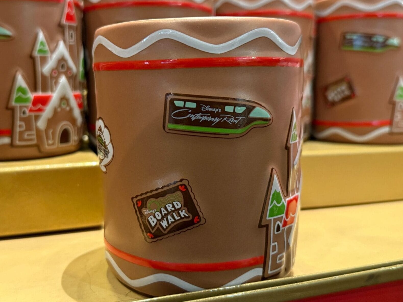 Gingerbread-themed mugs with Disneyland Resort designs on a shelf, featuring park icons distinct from Disney World castles.