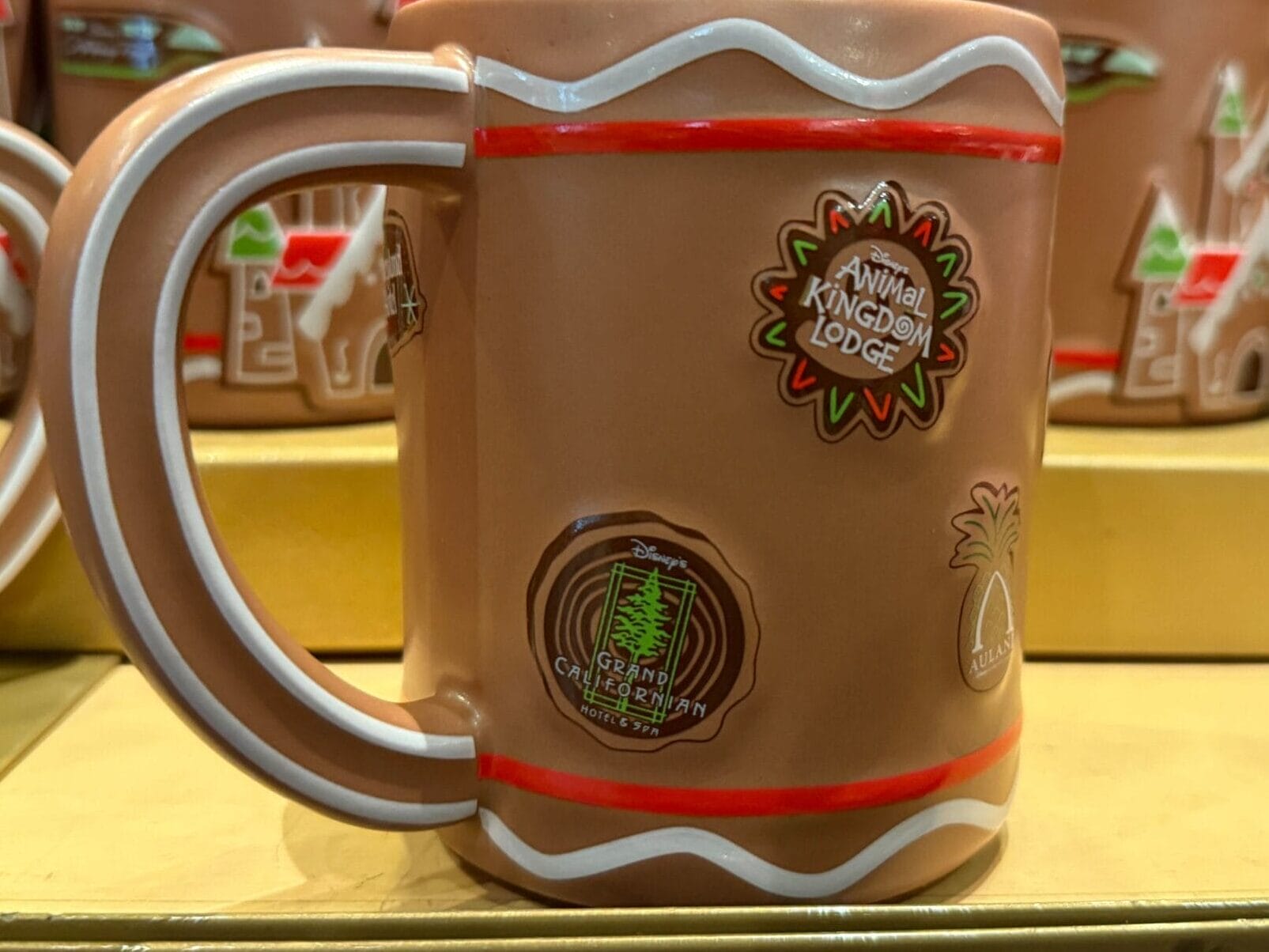 A brown Animal Kingdom Lodge mug sits among Disney holiday gingerbread items, evoking the park’s distinctive resort atmosphere.