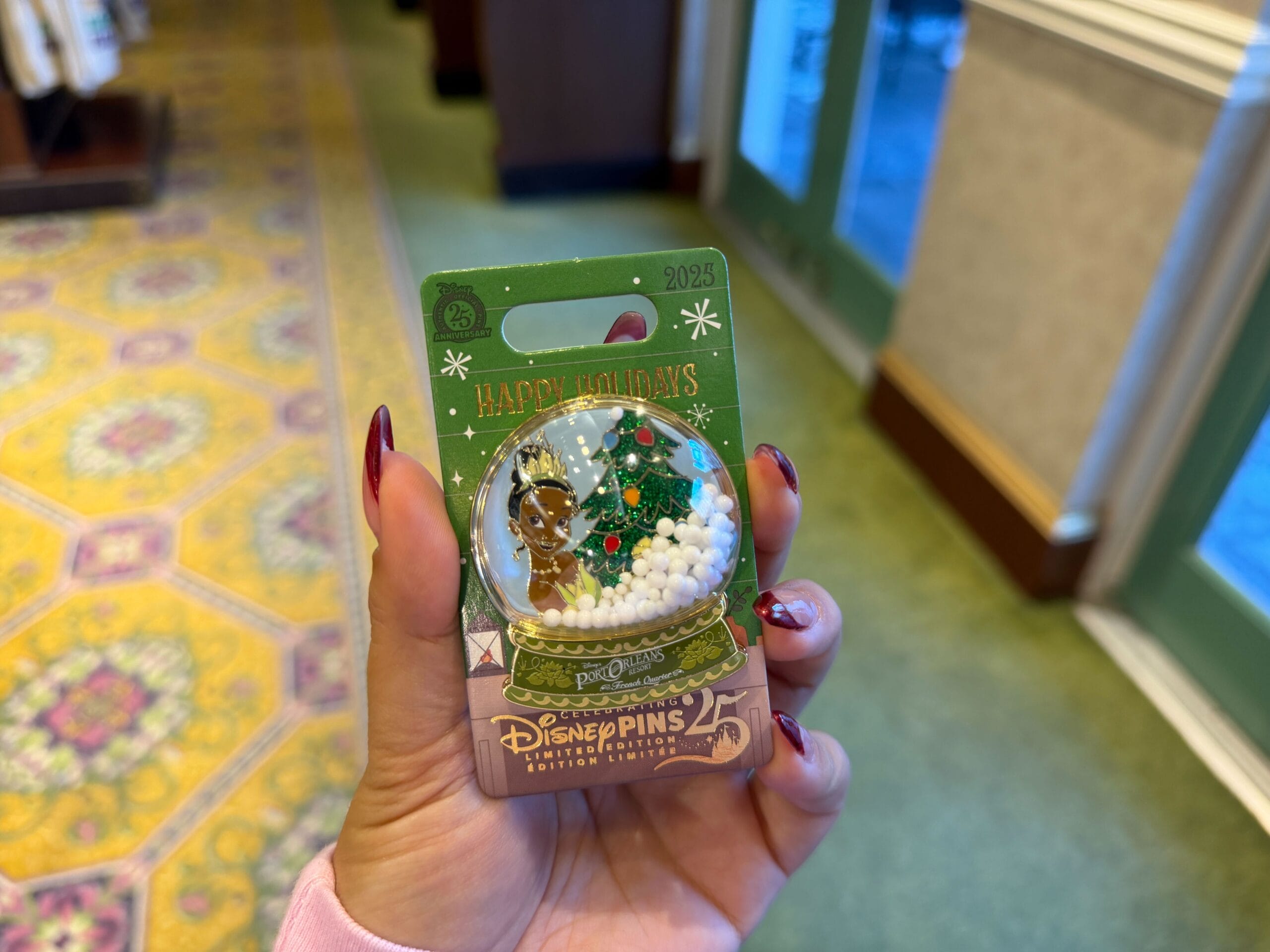 Hand holding a 2023 Walt Disney World holiday pin with Chip and Dale, a snow globe, and Christmas tree—no castle shown.
